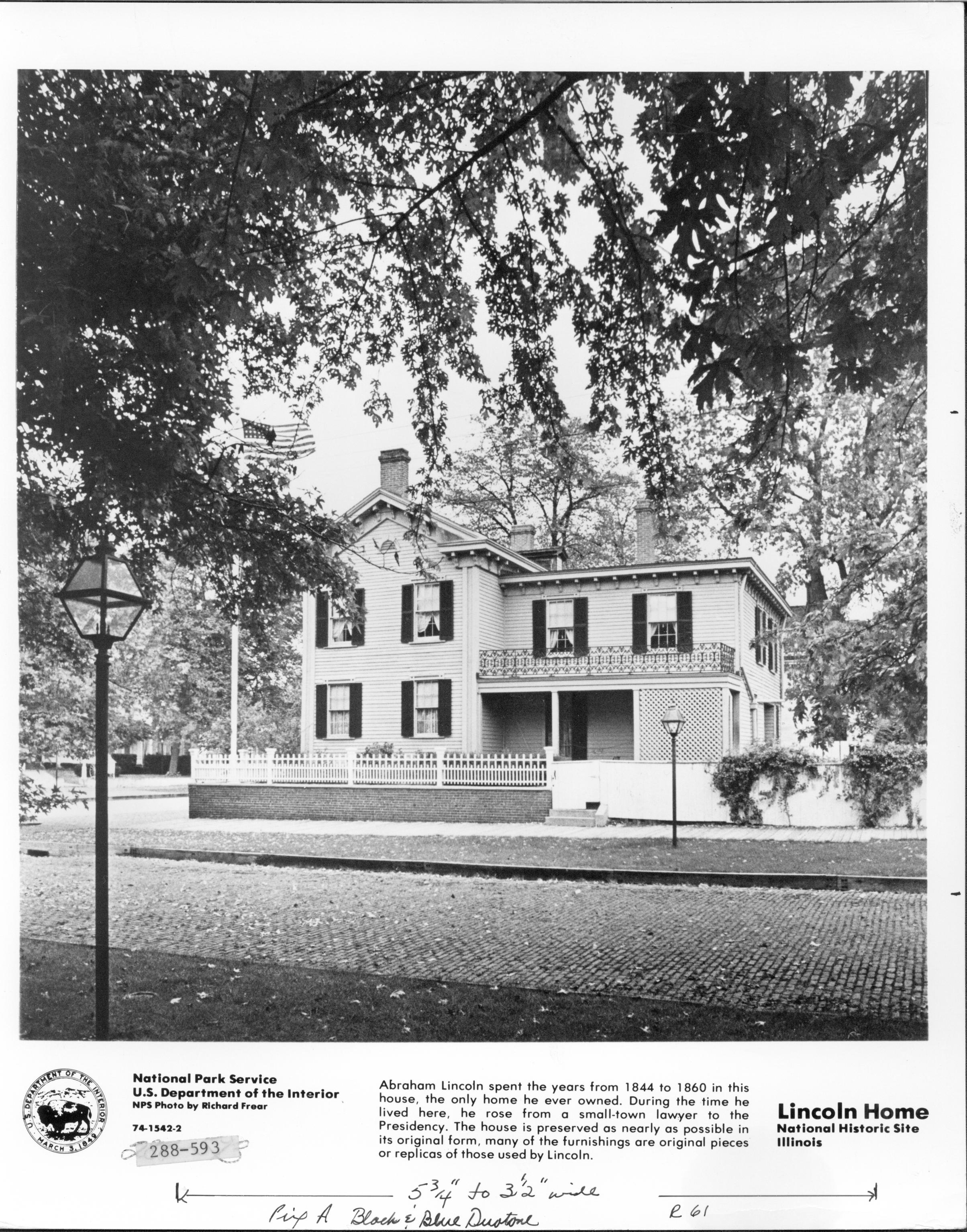 Official Lincoln Home photograph showing the South elevation. Jackson Street in foreground is bricked over. Dean House in far left background. Information about the site includes a logo for the Dept. of Interior. Hand written notes on the information bar imply use for an exhibit. Typed reference number also taped on. Looking Northwest from south of Jackson Street. Lincoln Home, DOI, Jackson, Dean, exhibits