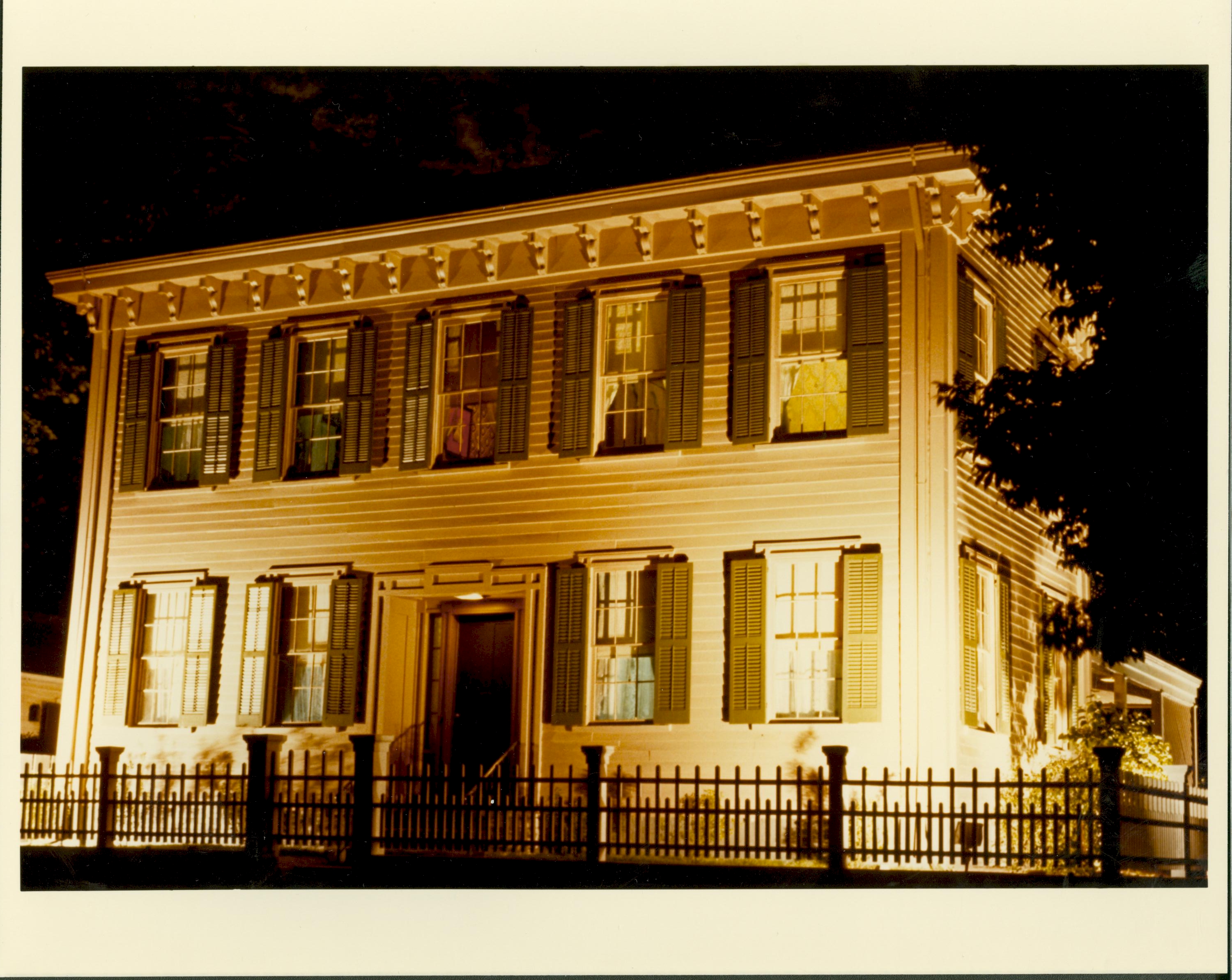 Lincoln Home front (West) elevation at night. Lights are visible inside Home. Tall tree on right. Looking Northeast from 8th and Jackson Street intersection. Lincoln Home, night