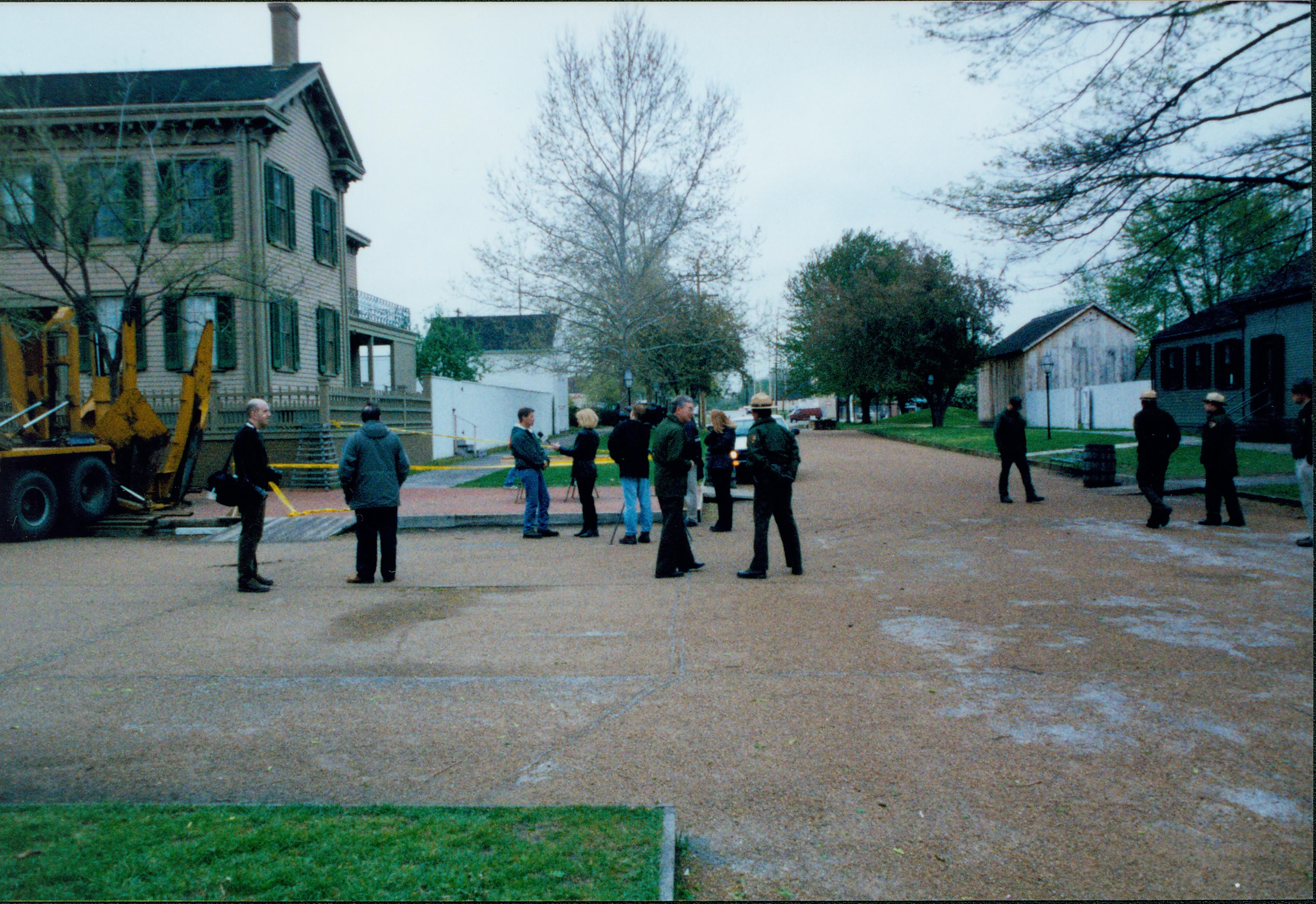 Elm tree replacement - Media Coverage in front of Lincoln Home. Superintendent Norman Hellmers chats with LE ranger Pete Swisher while reports talk to nursery staff. Maintenance Worker Vee Pollock and rangers watch with visitors on right near Arnold House. Unpainted Arnold Barn on right. Lincoln Home and Lincoln Barn on left.  Looking East from 8th and Jackson Street intersection Elm tree, Lincoln Home, Arnold, Arnold Barn, 8th Street, Jackson Street, staff, reporters, Pleasant Nursery