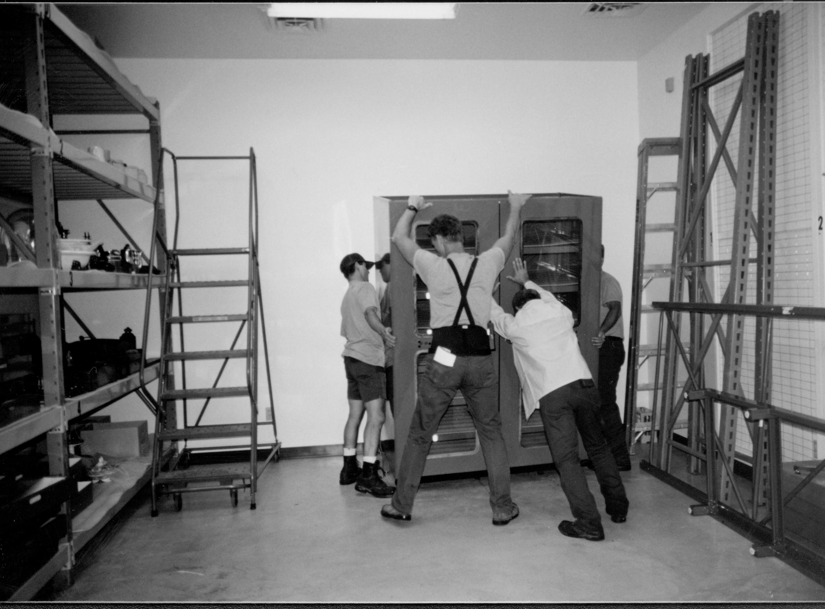 Moving large gray sorage cabinet into new location. Southeast corner at right of photo Lincoln Home NHS, CRS Collection Move, Facing East Wall, Roll N10, exp 5 sheet 2 of 7 Arnold Barn, renovation