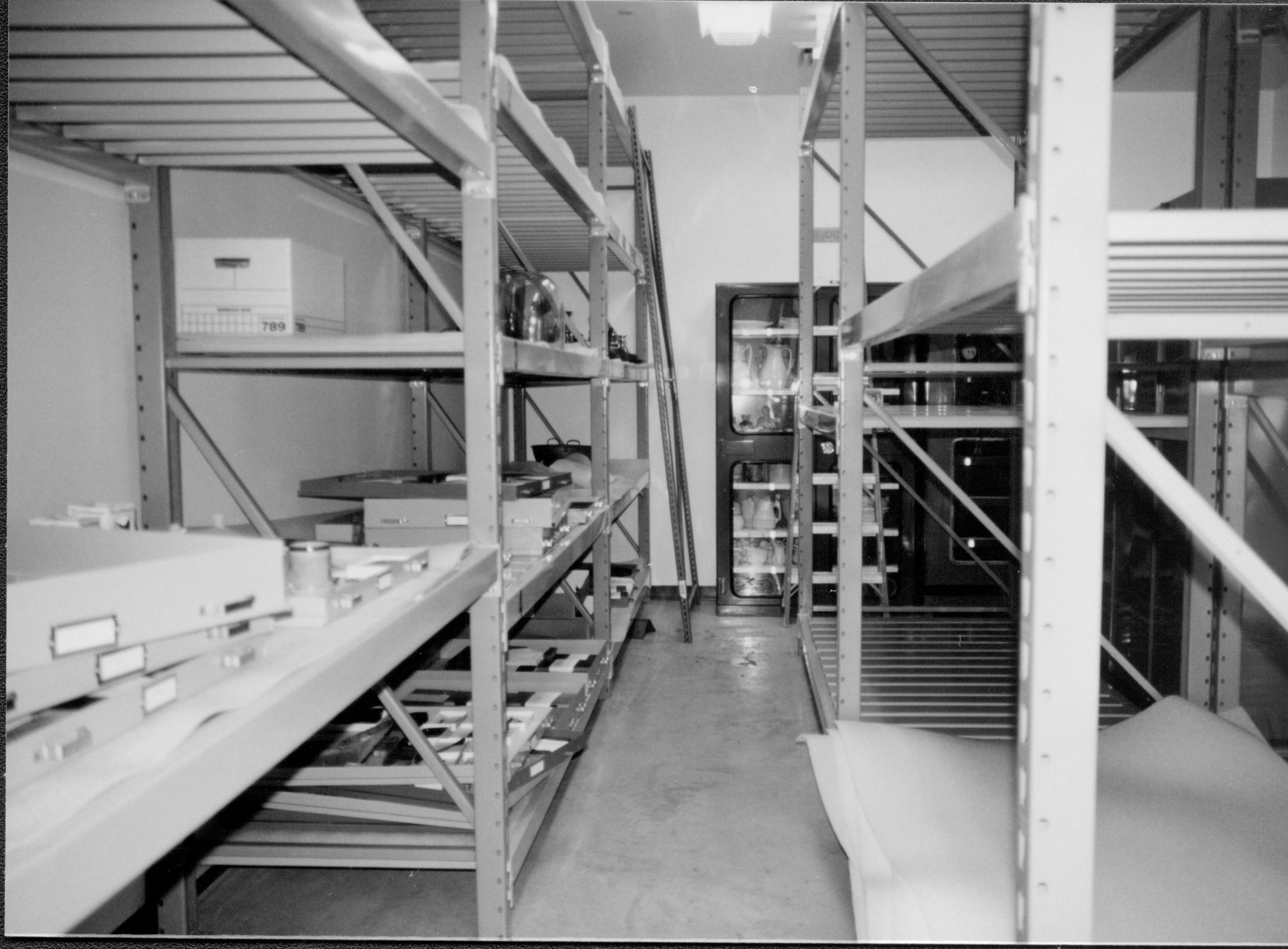 Artifacts for storage in book cabinets prepared for installation. Book cabinet seen at extreme left of photo behind center storage racks Lincoln Home NHS, CRS Collection Move, North and East Wall, Roll N10, exp 19 sheet 5 of 7 Arnold Barn, storage, artifacts