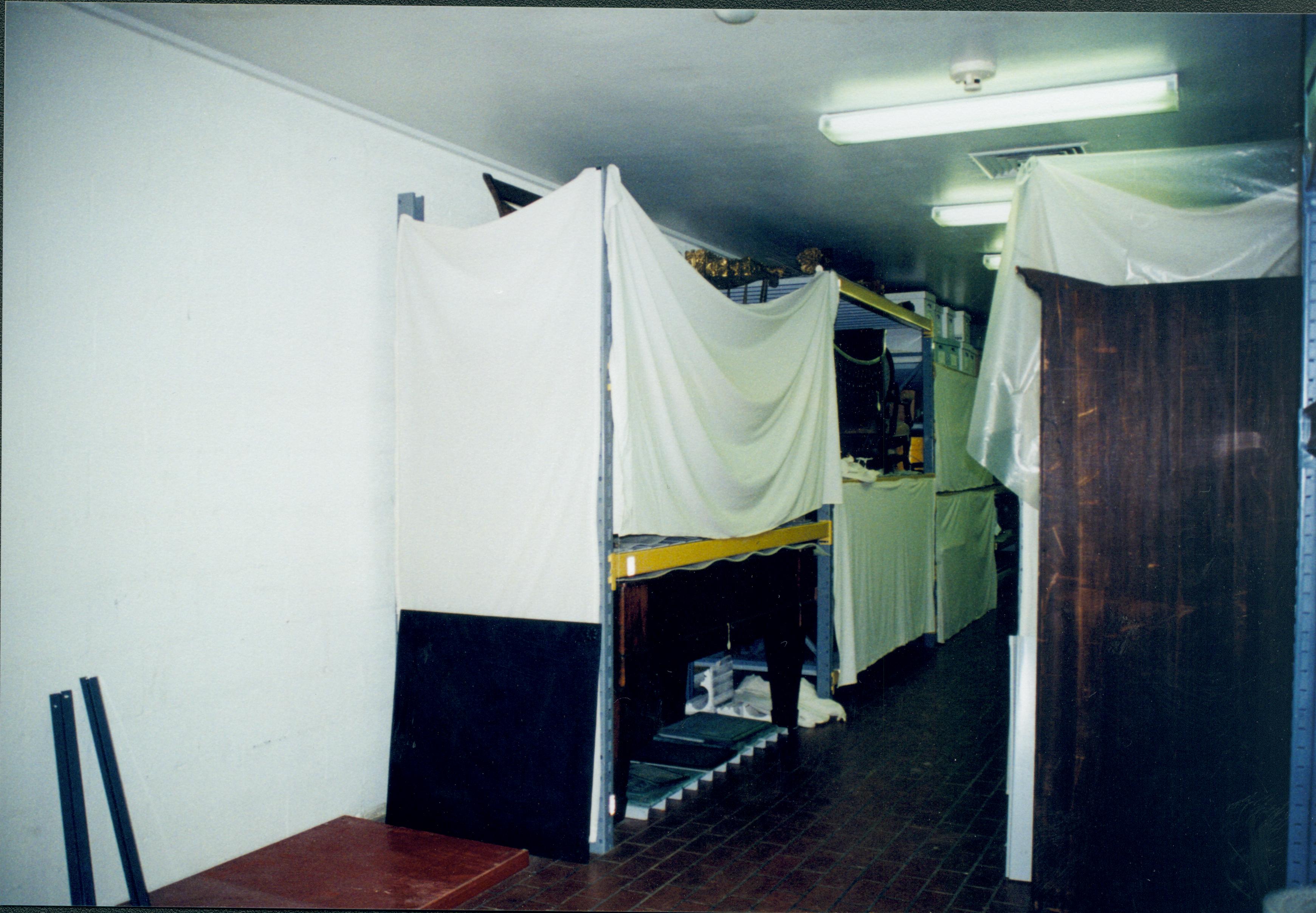 Looking South-Southeast (standing with back against wall, Northwest corner) along the aisle between 4 foot racks. In left foregrounds can see empty space where glass fronted, gray cabinets were. Lincoln Home NHS, 1998 CRS Collection Move, Roll N7, exp 3 sheet 1 of 9 Carriage House, storage room