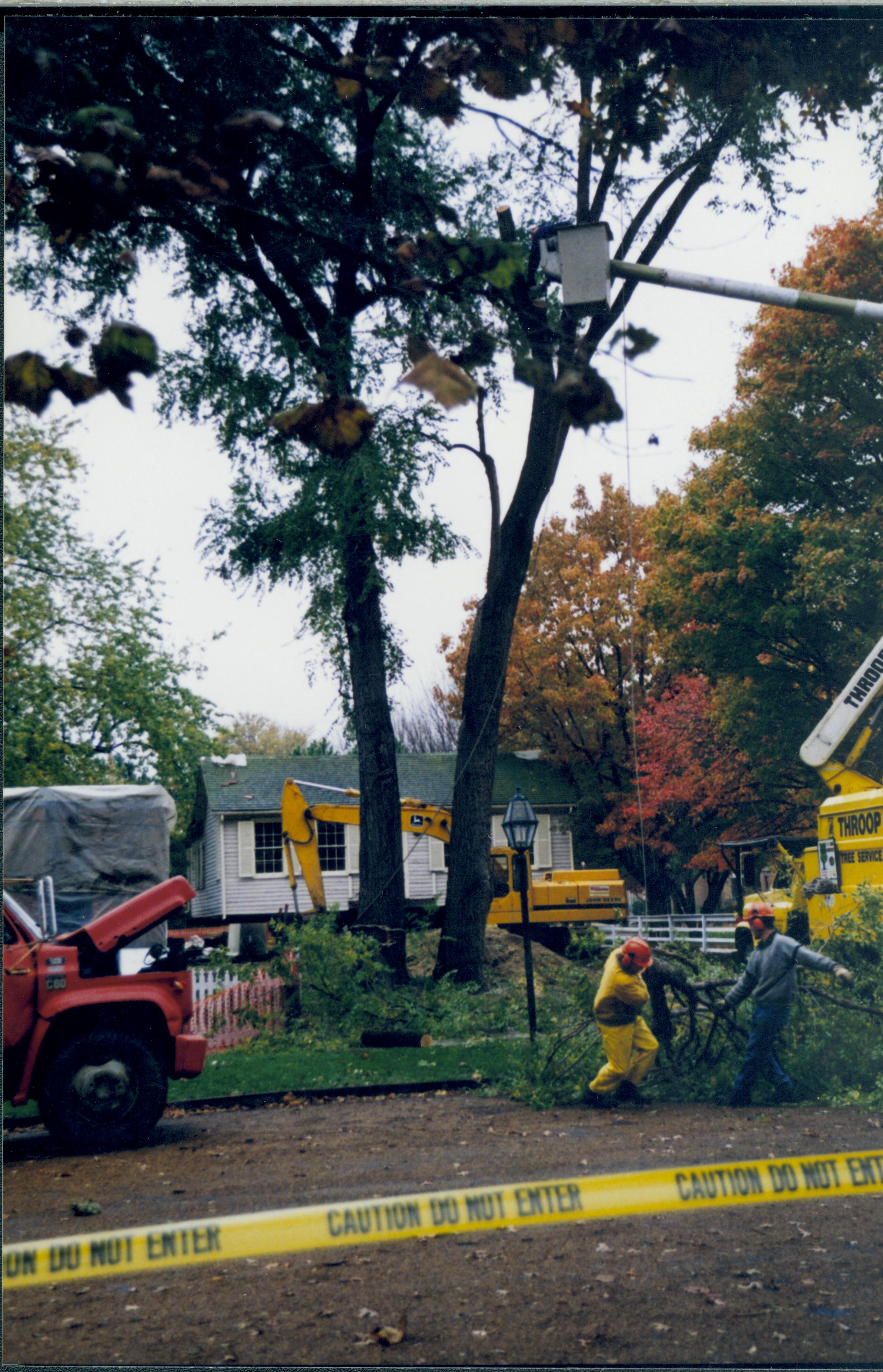 Cutting down trees at Southwest corner of 8th/Jackson intersection; in prep for moving Corneau House to front of lot. East elevation in background. Photo taken from East side of 8th St. Lincoln Home NHS- Corneau House and Lot, Roll N5 exp 4 Corneau, move