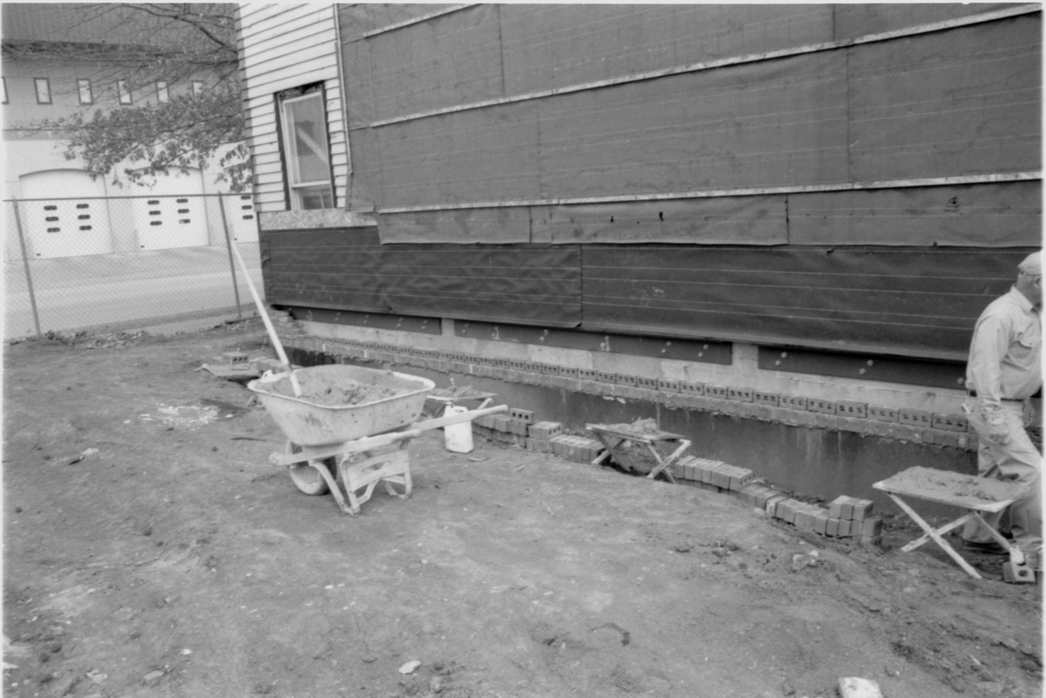 Morse - restoration, laying brick around foundation. Contract mason on right. Fire Station No. 1 in background left. Looking North/Northeast from Morse Lot (Block 10, Lots 15-16) Morse, foundation, restoration, brick, mason, Fire Station No. 1