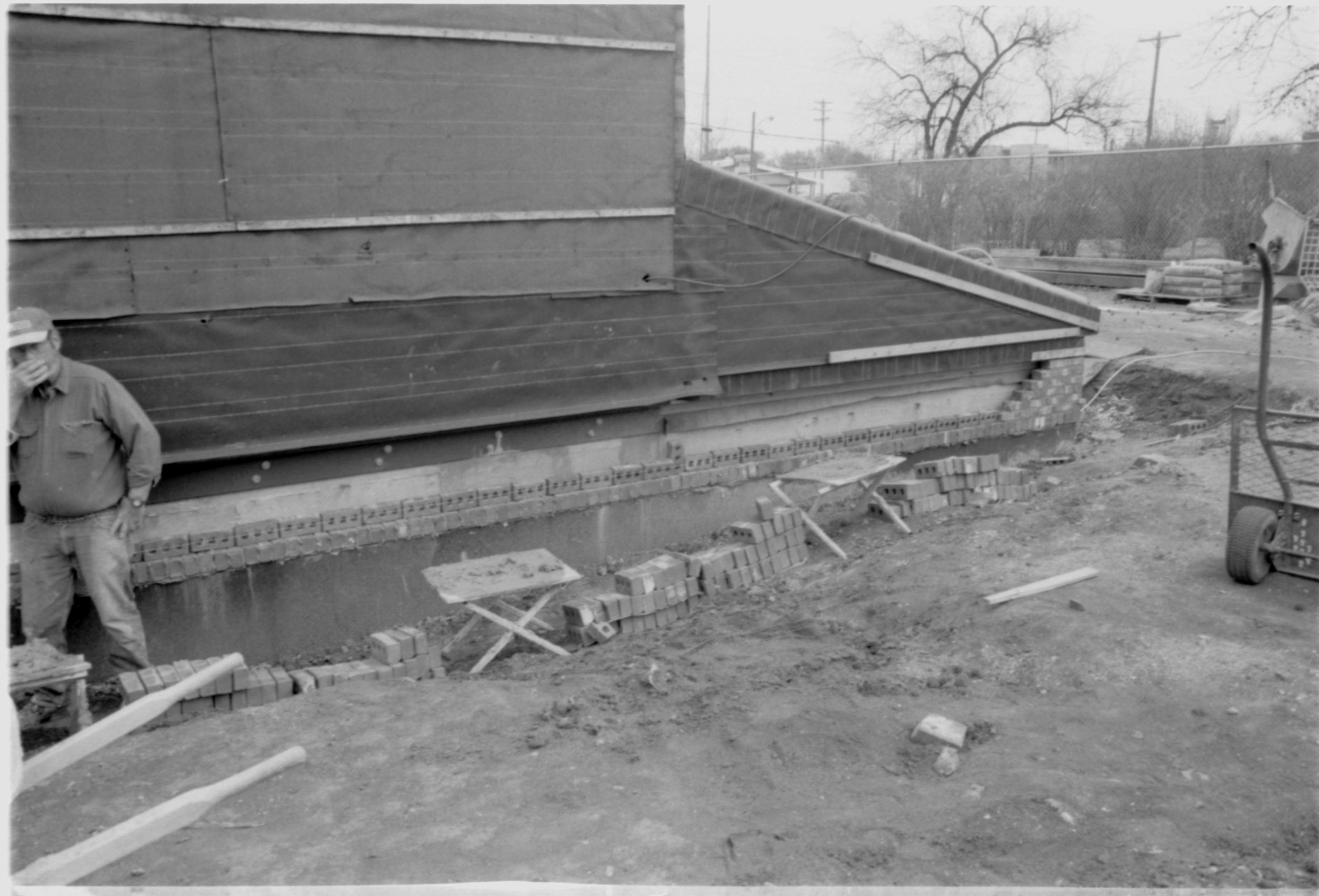 Morse - restoration, laying brick around foundation. Contract mason on left. Former Travel Lodge Motel in far background right. Looking Southeast from Morse Lot (Block 10, Lots 15-16) Morse, foundation, restoration, brick, mason, Travel Lodge