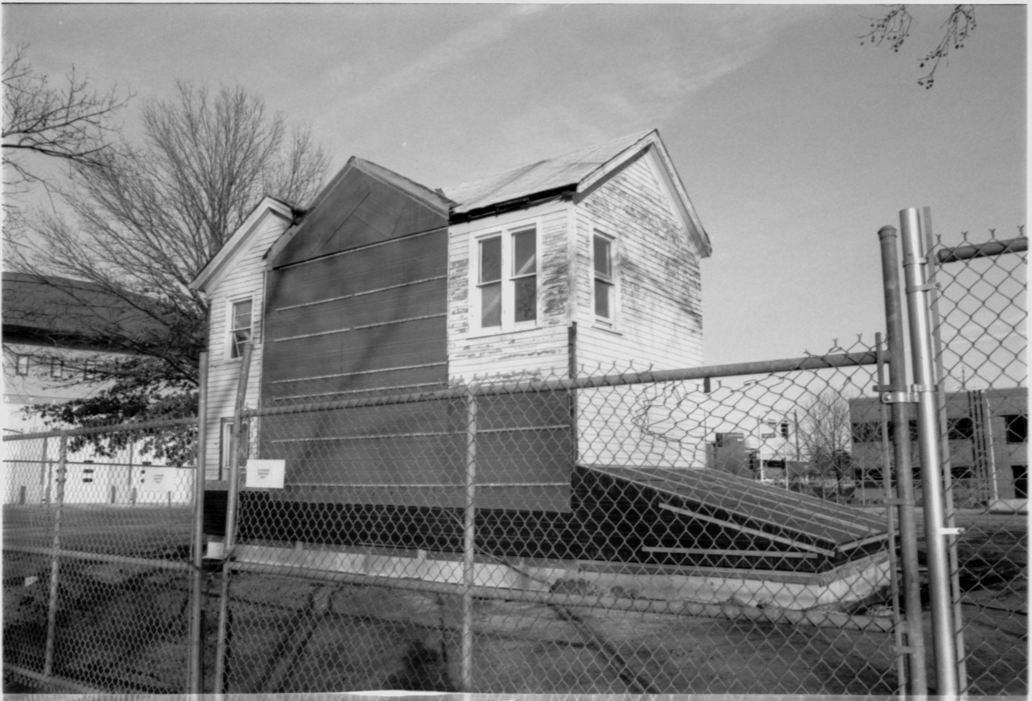 Morse - restoration, stabilization for winter. Chain link fence surround. Fire Station No. 1 in background left. Office buildings across 9th Street in background right. Looking Northeast from alley by Morse lot (Block 10, Lots 15-16) Morse, restoration, stabilization, Fire Station No. 1, 9th Street