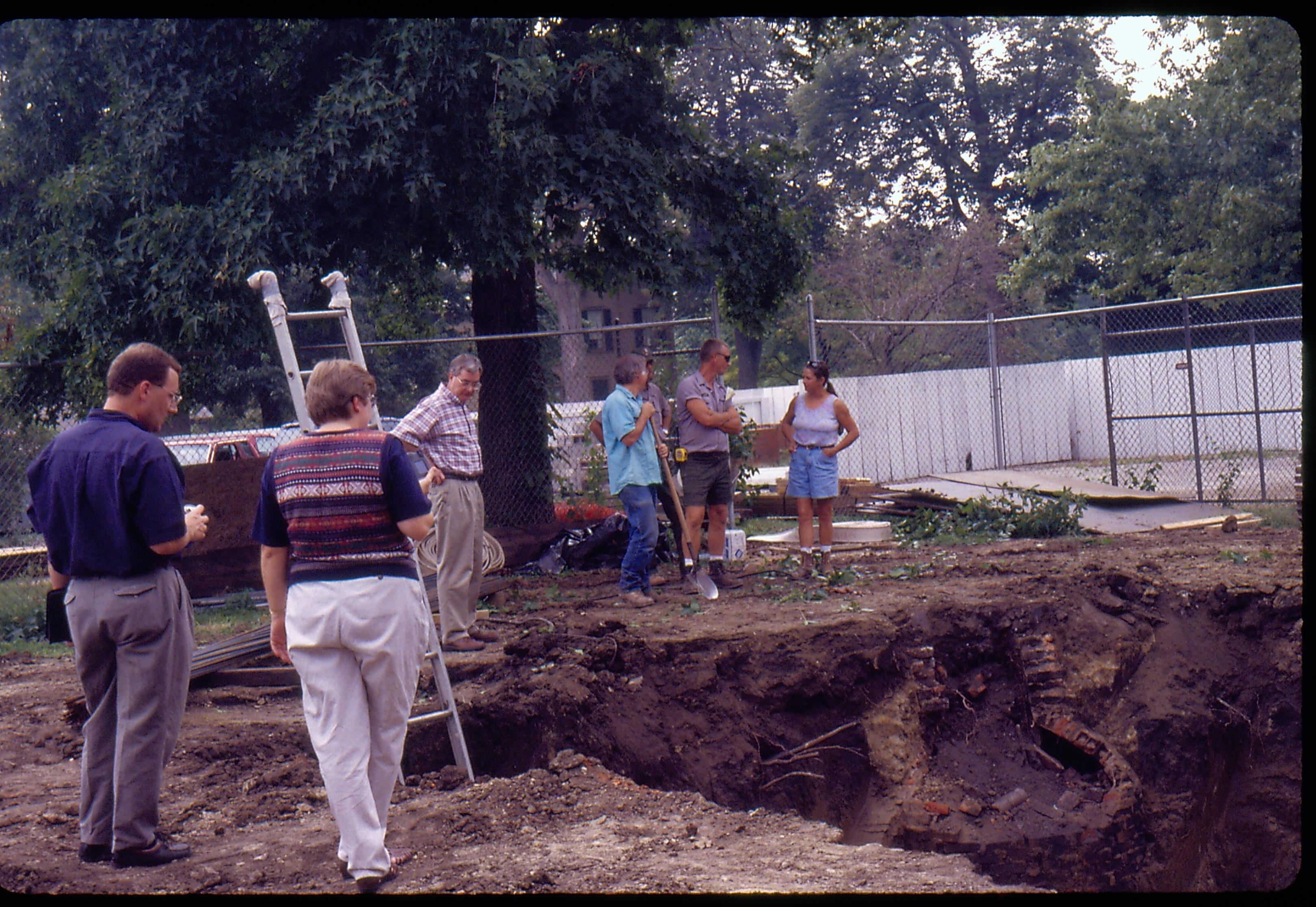 Morse - basement excavation. Historian Tim Townsend, Curator Susan Haake, Supt. Norman Hellmers, Maintenance Workers Ed Smith and Doug Sharp chat with contract archeology staff from Fever River. Archeologist Floyd Mansberger with shovel. Brick cistern in on right. Lincoln Home in background right Looking Southwest from Morse Lot (Block 10, Lots 15-16) Morse, foundation, archeology, cistern, Lincoln Home,staff, Fever River