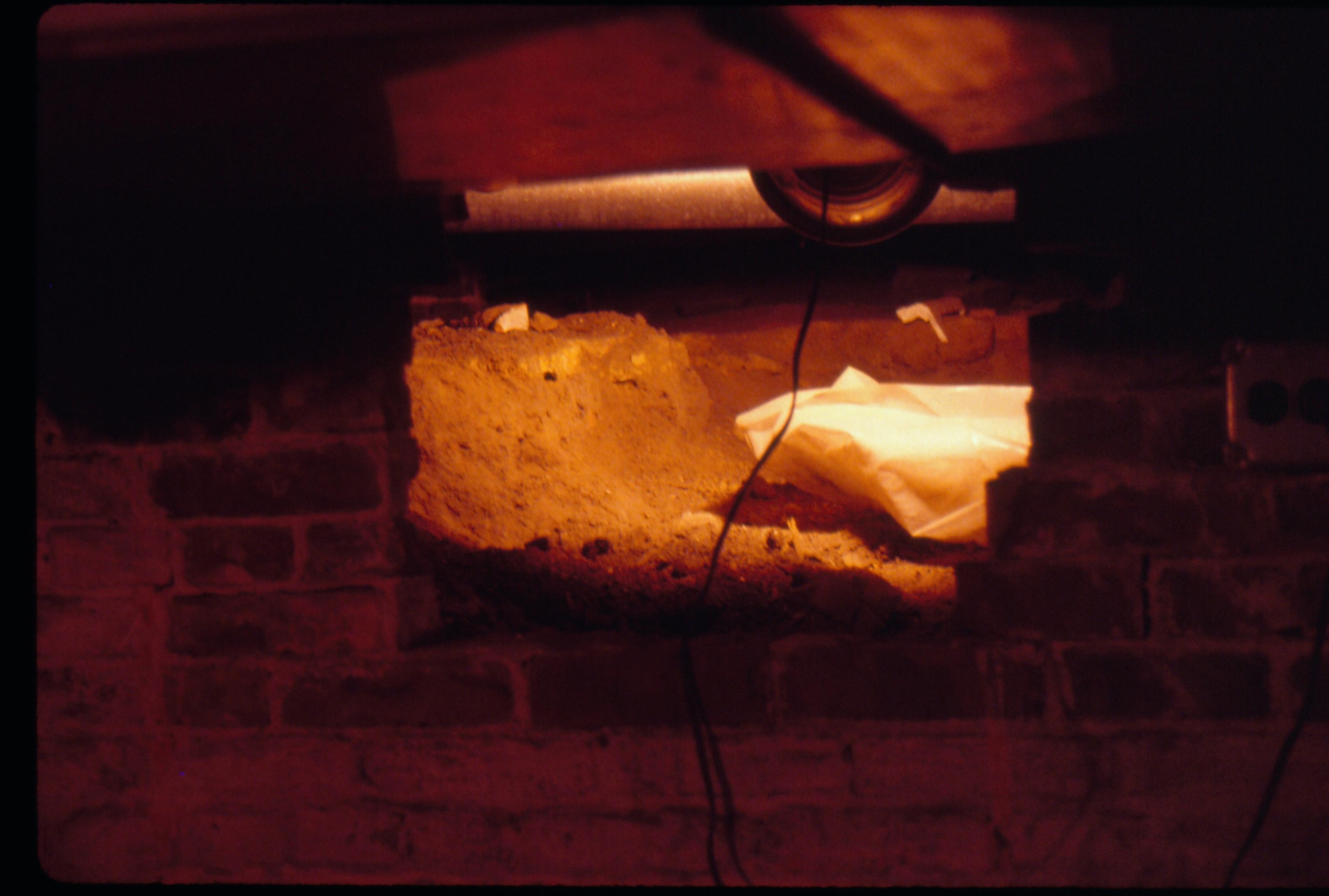 Lyon House - Crawlspace showing wires hanging from ceiling for safety light hangin in opening of brick wall. Opening in wall has dirt, sand, and white plastic bag?  Looking East in basement Lyon, Basement, brick wall, crawlspace
