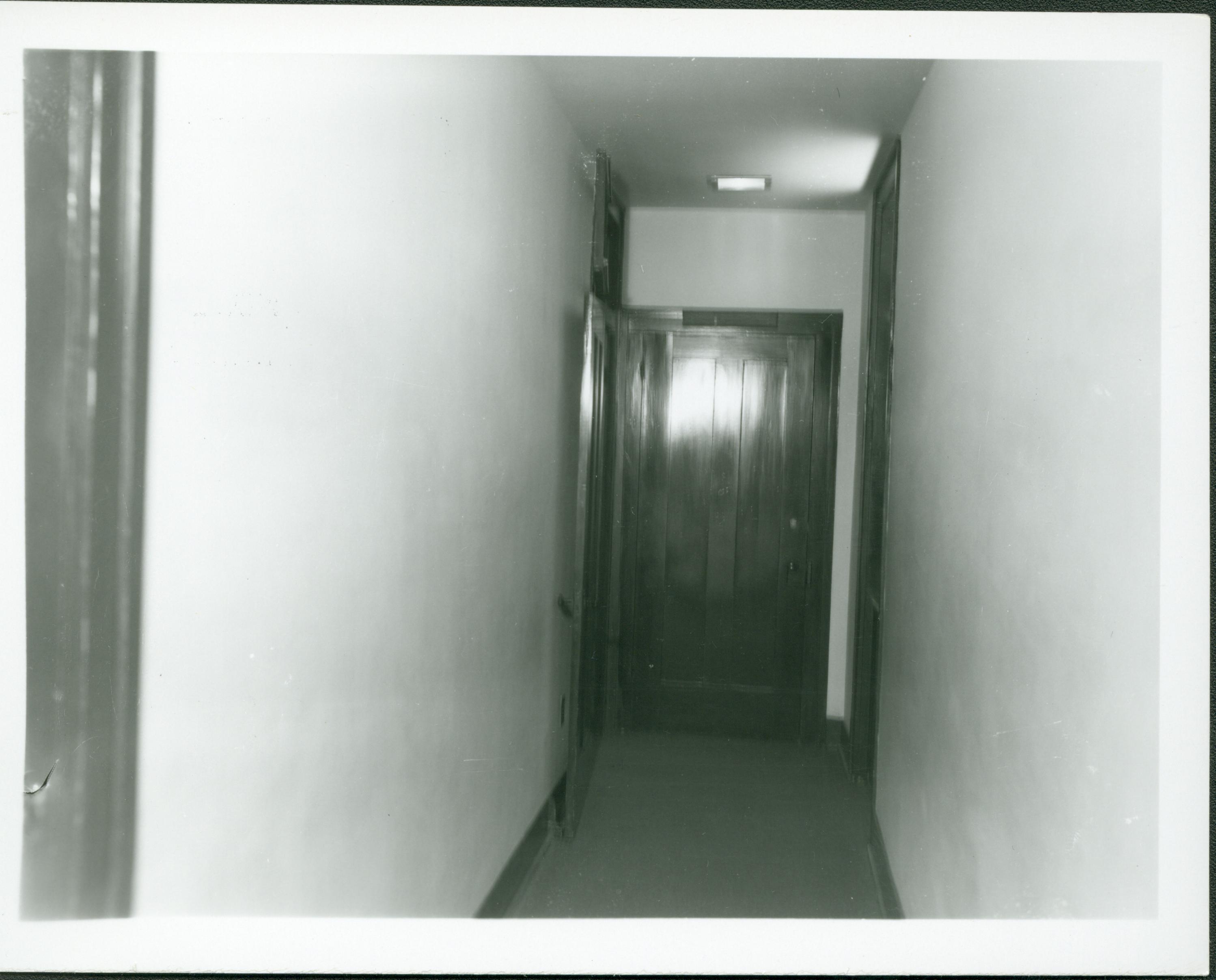 Second floor back hall prior to restoration, circa 1974. Photographer facing west. Note the now-demolished and relocated doorway and transom to Boy's room on left side of hall in background.