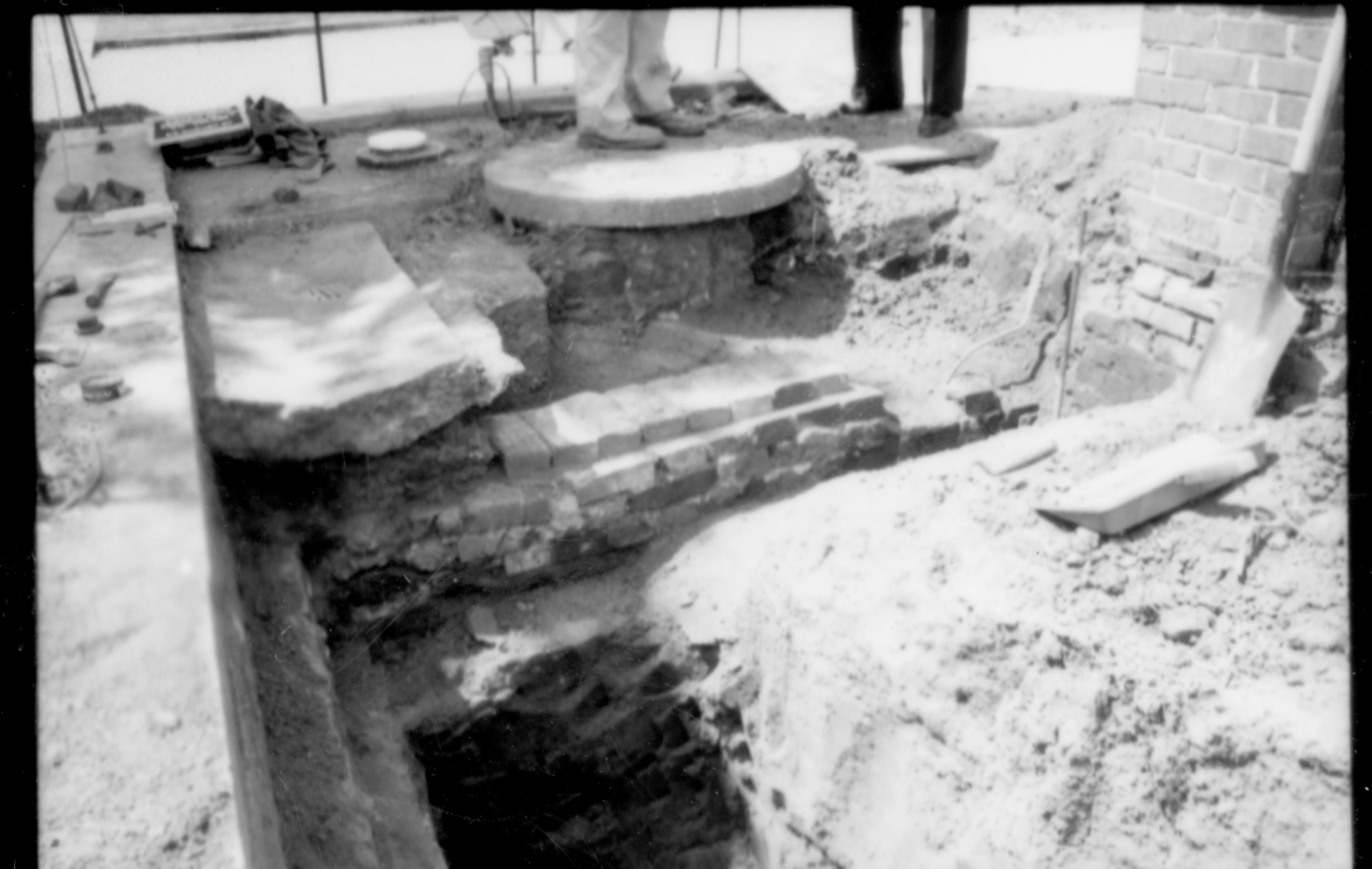Sewer cap, drains, unidentified brick section, and south and west retaining wall on the south west corner of the Lincoln Home lot. The south west corner and brick column base of the Lincoln home can be seen on the right side of the photo. Photographer facing west.
