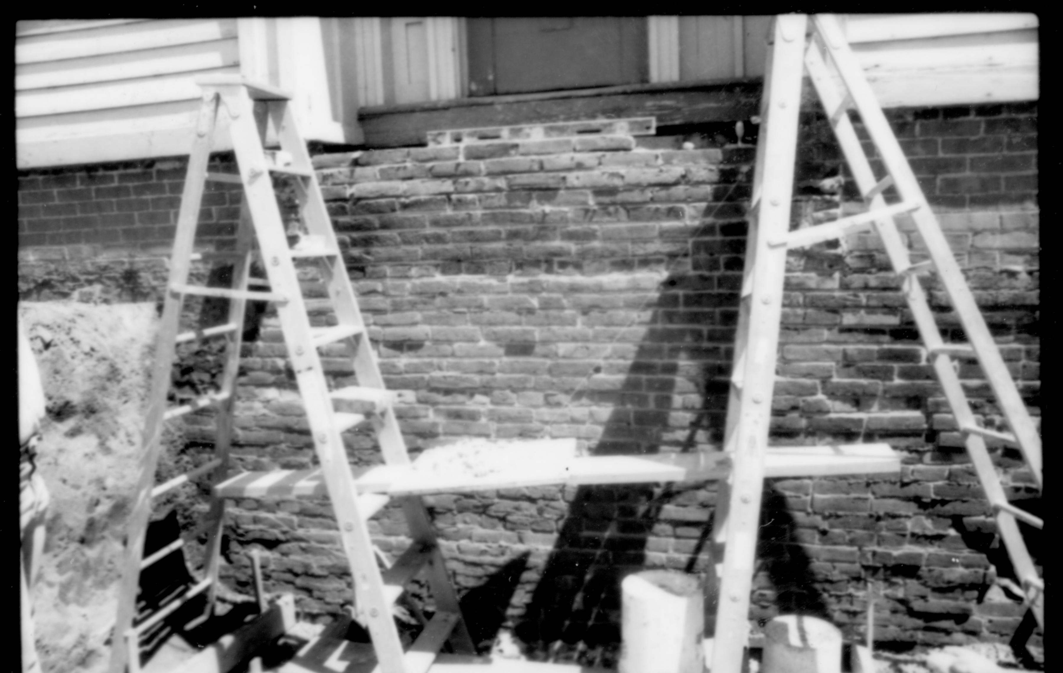 A pair of ladders in a pit located in front of the retaining wall of the front entrace door of the Lincoln Home. Photographer facing east.