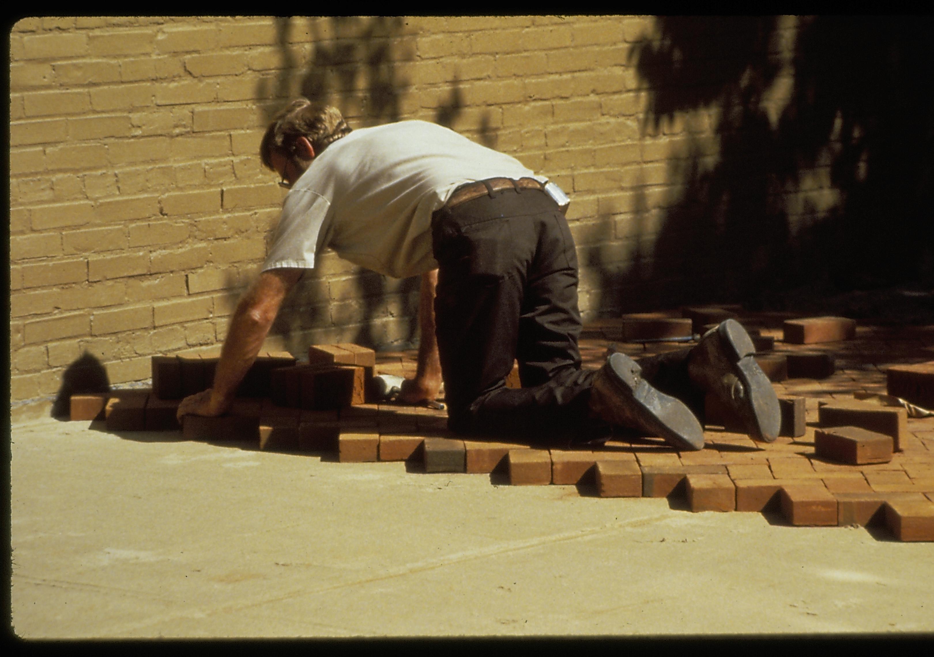 Bricklayer setting the bricks for the plaza in front (west) of the Lincoln Home during the 1987-88 Restoration. Photographer facing south east.