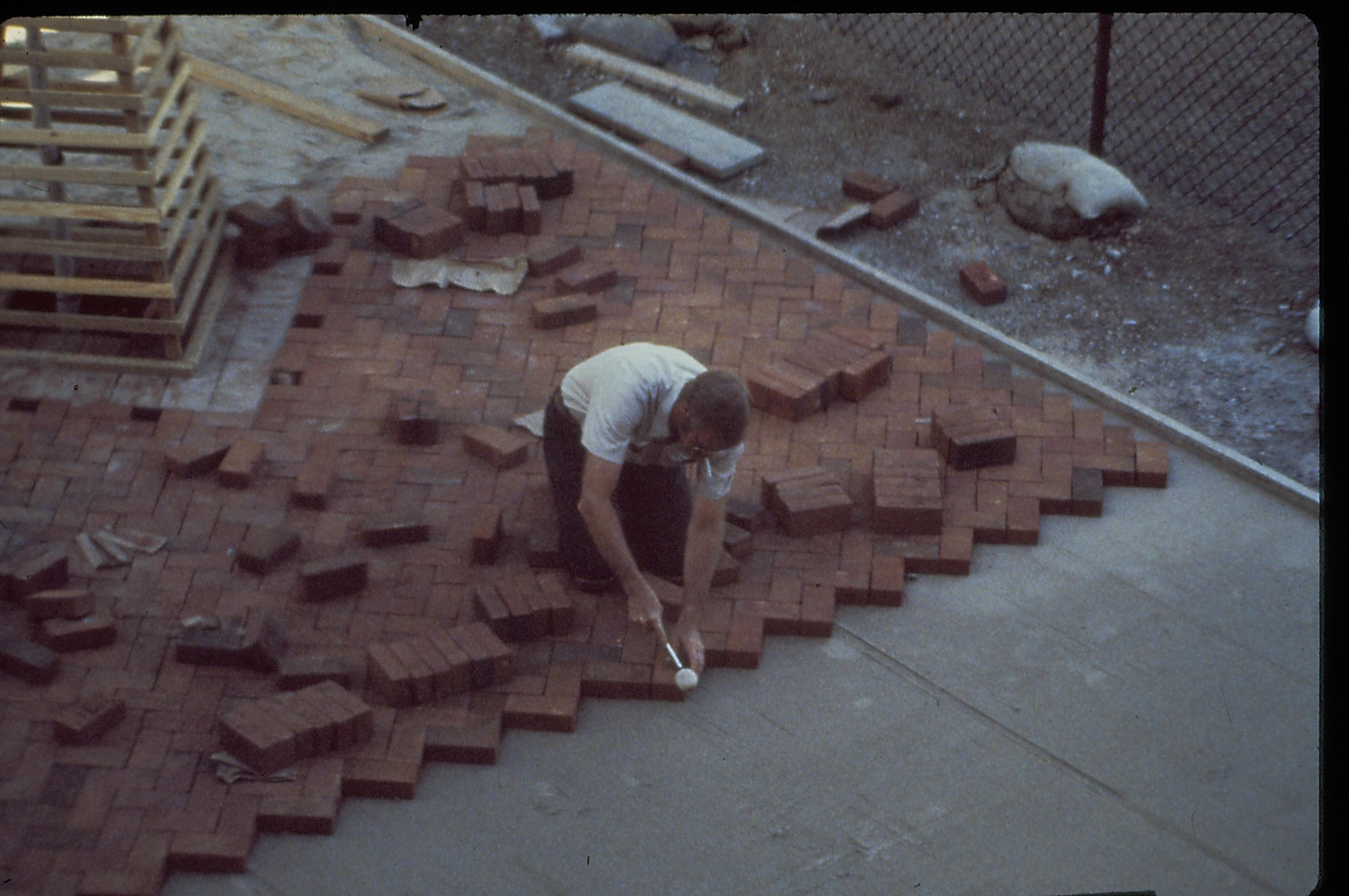 Bricklayer setting the bricks for the plaza in front (west) of the Lincoln Home during the 1987-88 Restoration. Photographer facing south west.