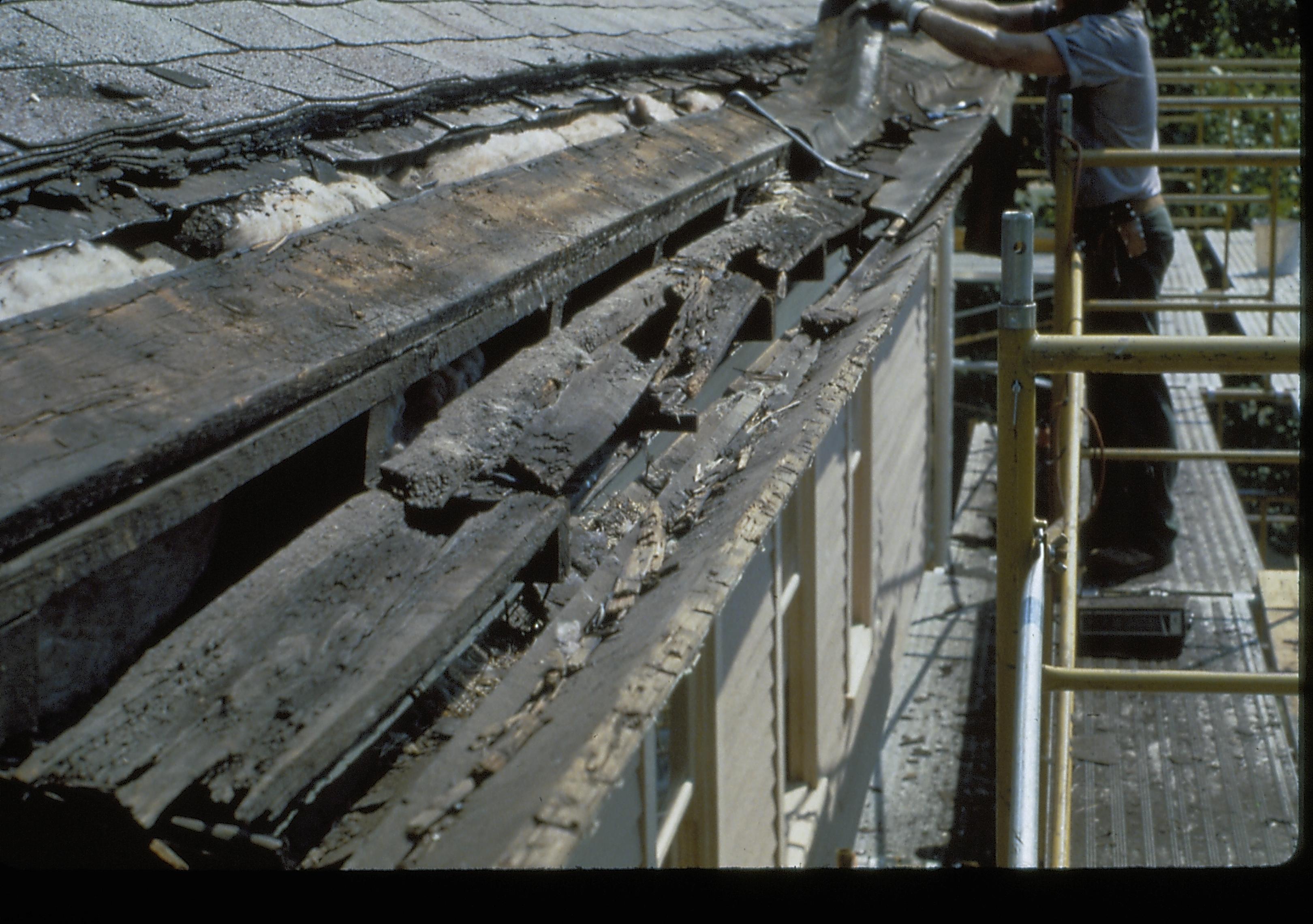 A section of demolished gutter above the second floor the Lincoln Home. A staff member continues demolition in the background.