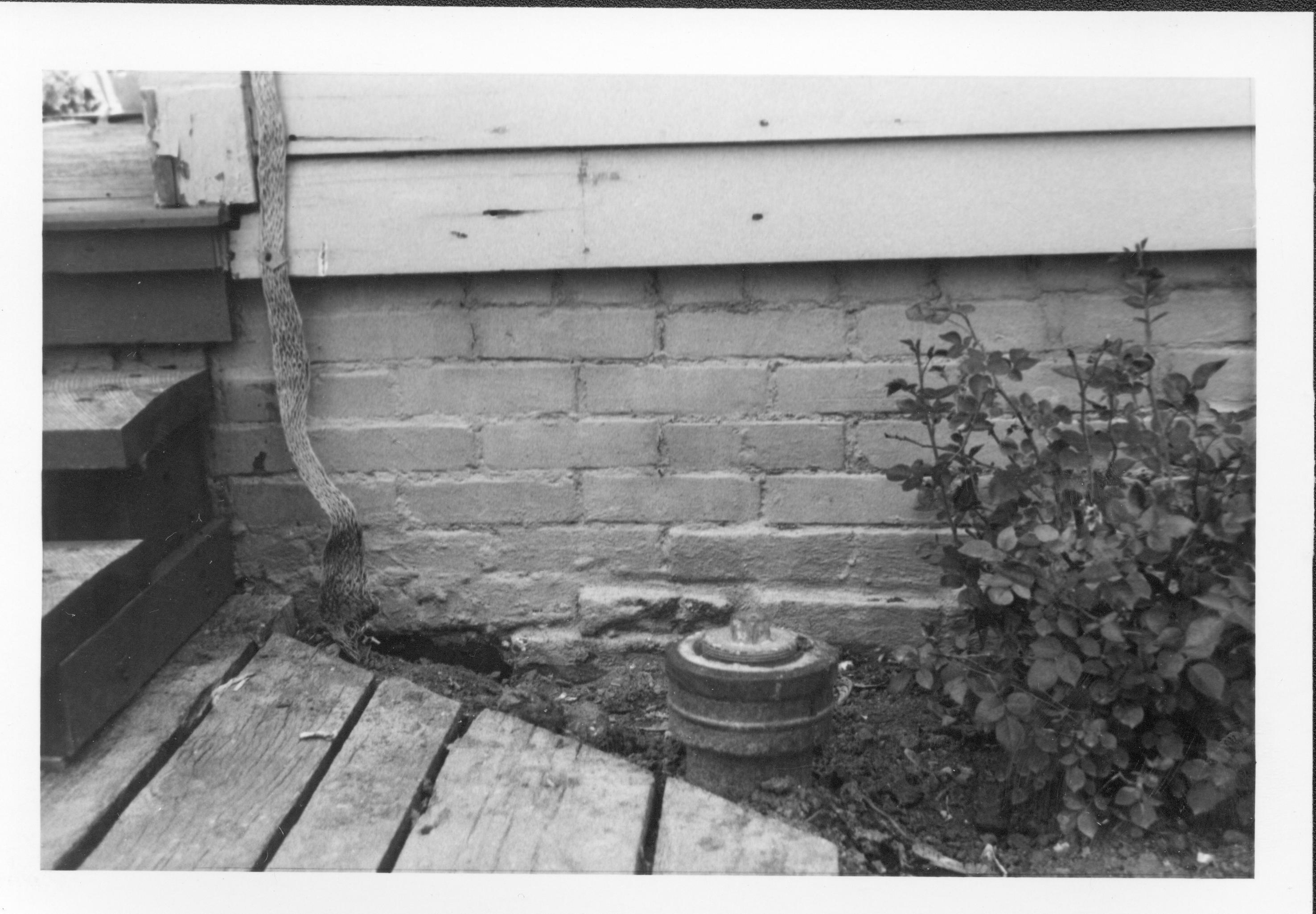 Drain pipe near the Lincoln Home foundation, east of the south porch and kitchen. Photographer facing west.