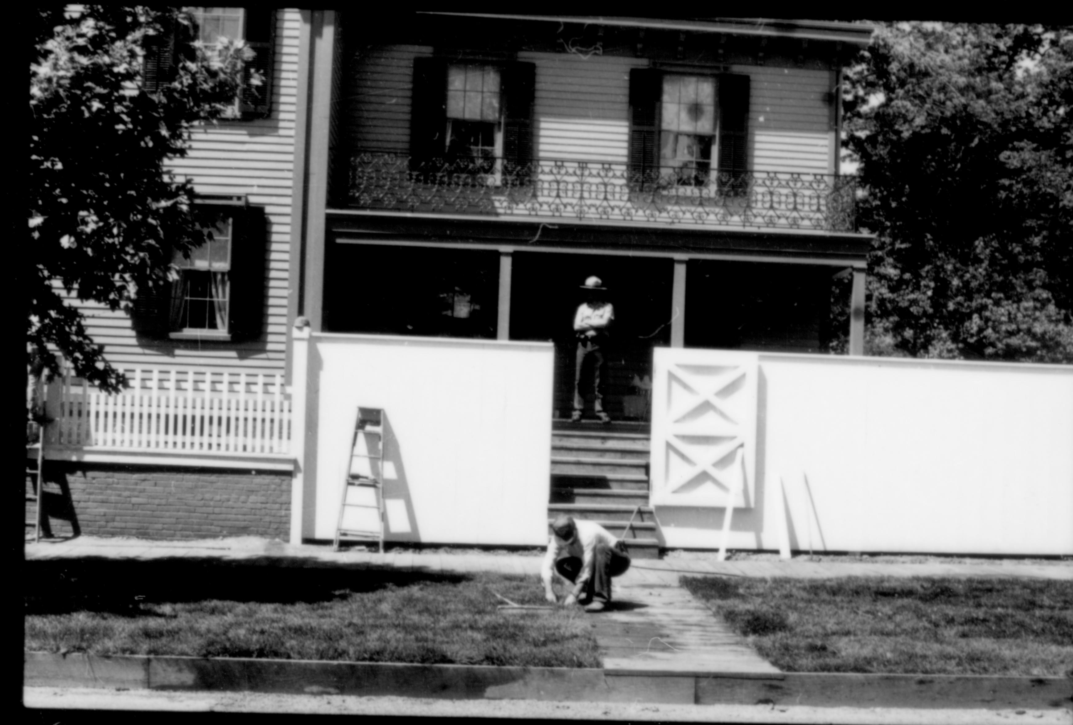 View of the south facing of the Lincoln Home during the 1987-88 restoration. One ranger on back porch, with two workers painting the fence. Photographer facing north.