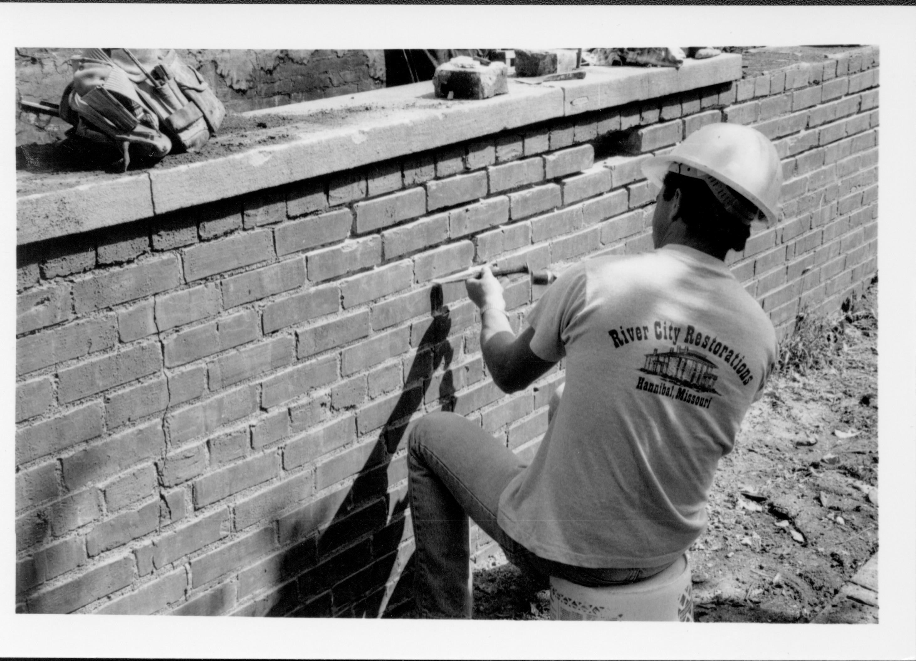 A worker from River City Restorations removes mortar from the retaining wall of the Lincoln Home, inpreparation for restoration/repair work.
