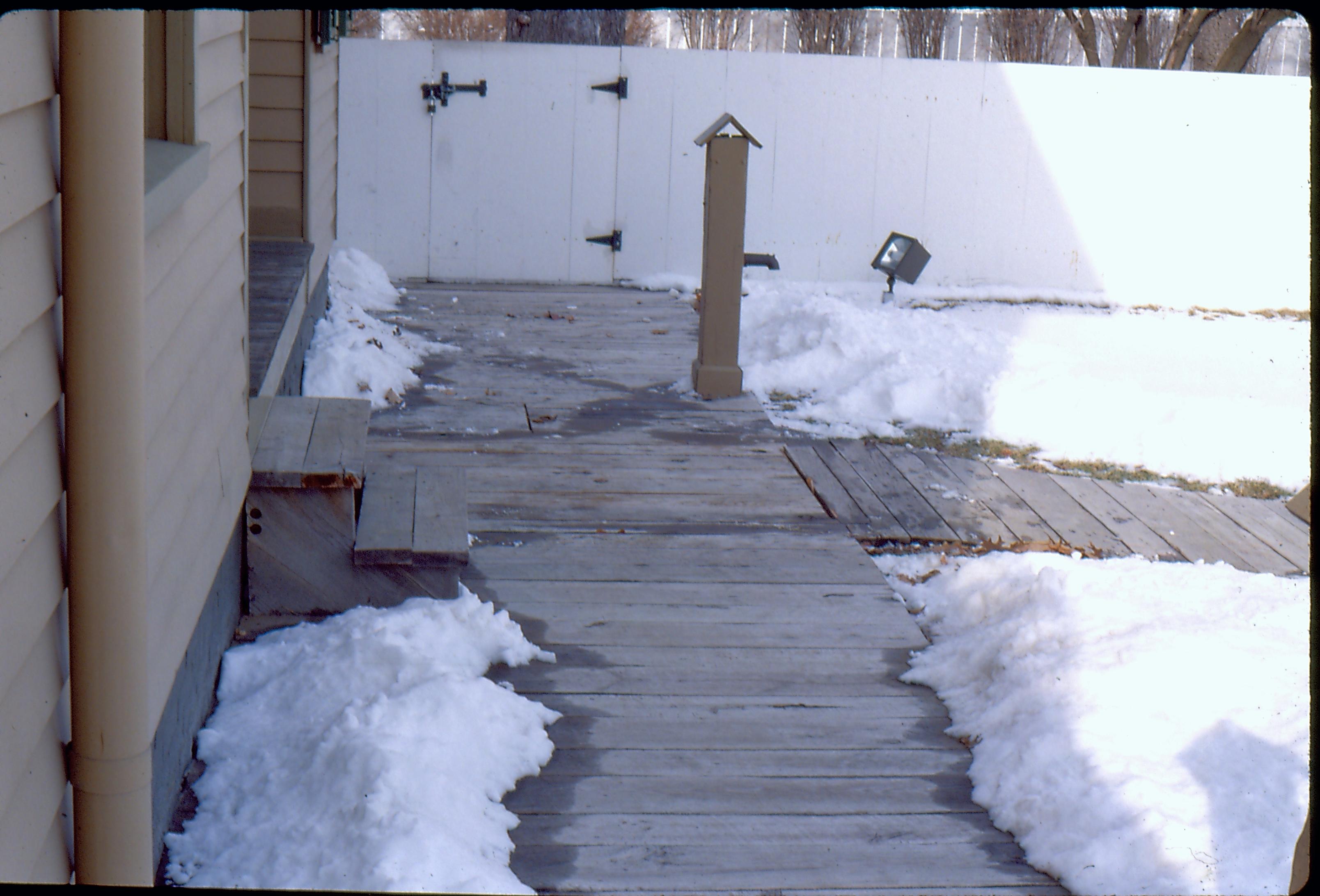 View of the Lincoln Home wheelchair lift, fully retracted without rails. Snow on ground. Photographer facing north.
