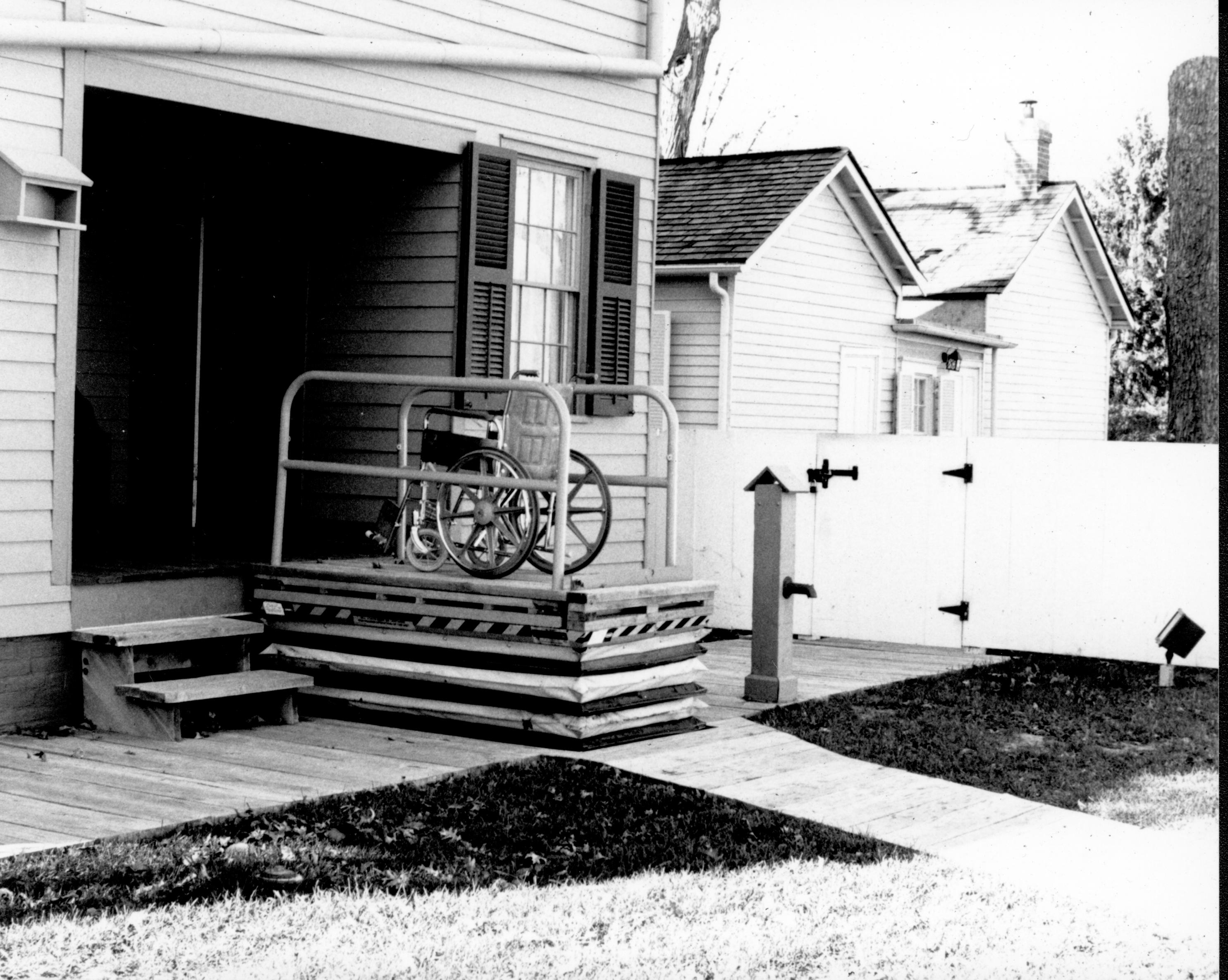Lincoln Home wheelchair lift at full height, with empty wheelchair. Photographer facing north west.