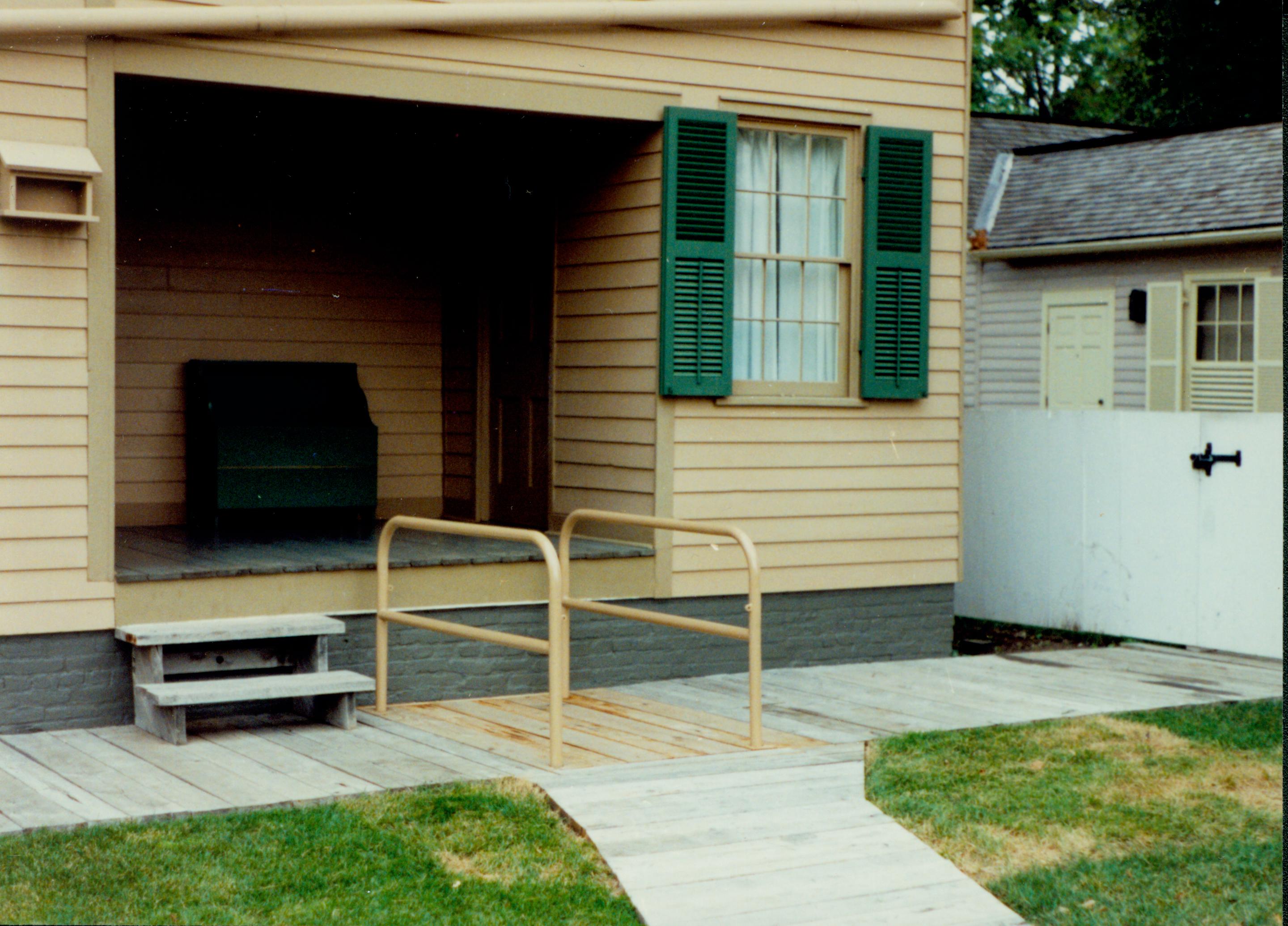 The wheelchair lift of the Lincoln Home fully retracted with handrails. Corneau house in background. Photographer facing north west.
