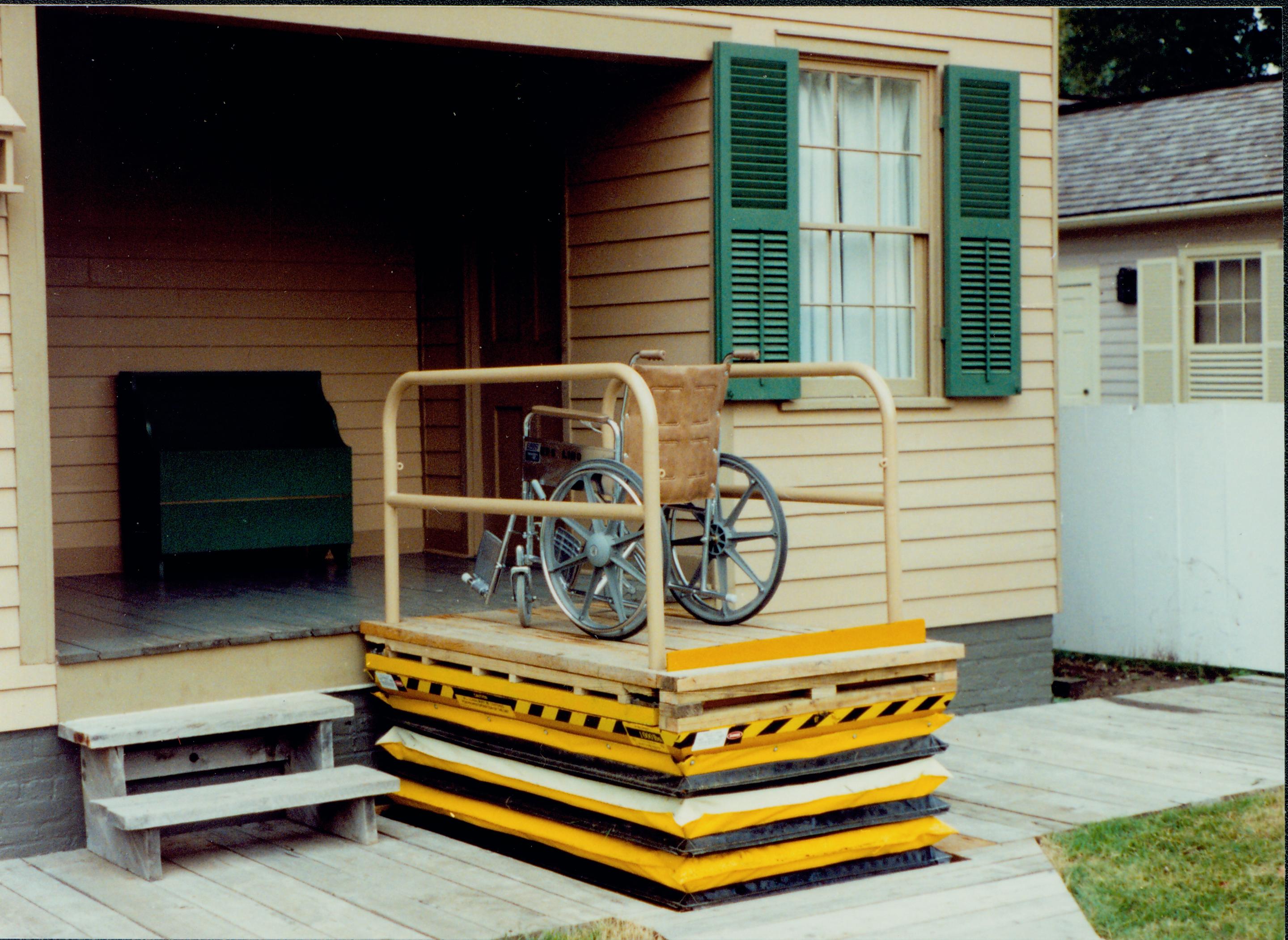 Lincoln Home wheelchair lift at full height, with empty wheelchair. Corneau house in background. Photographer facing north west.