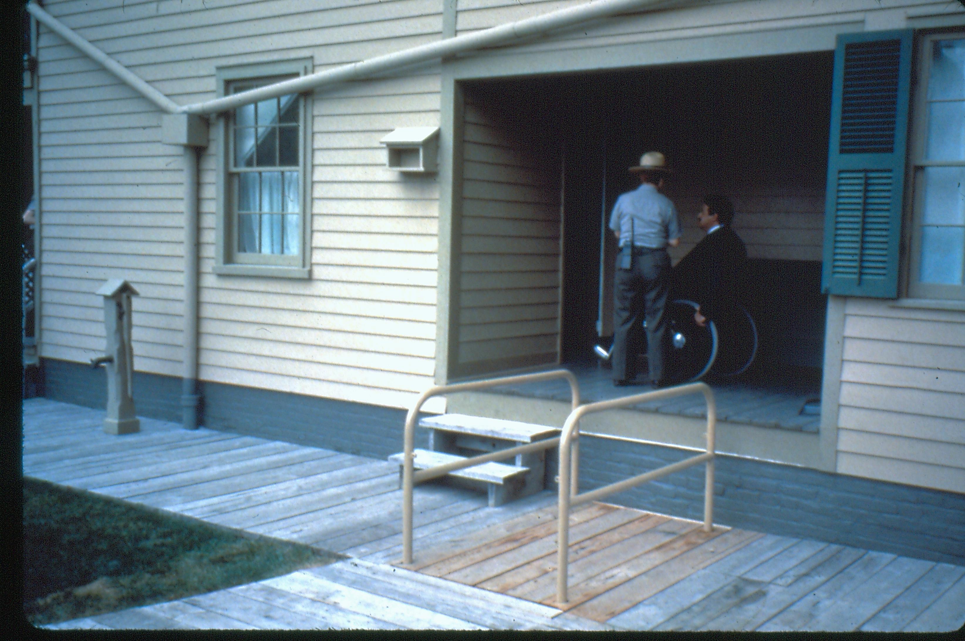Lincoln Home wheelchair lift. Staff member and visitor in wheelchair on East porch. Photographer facing south west.