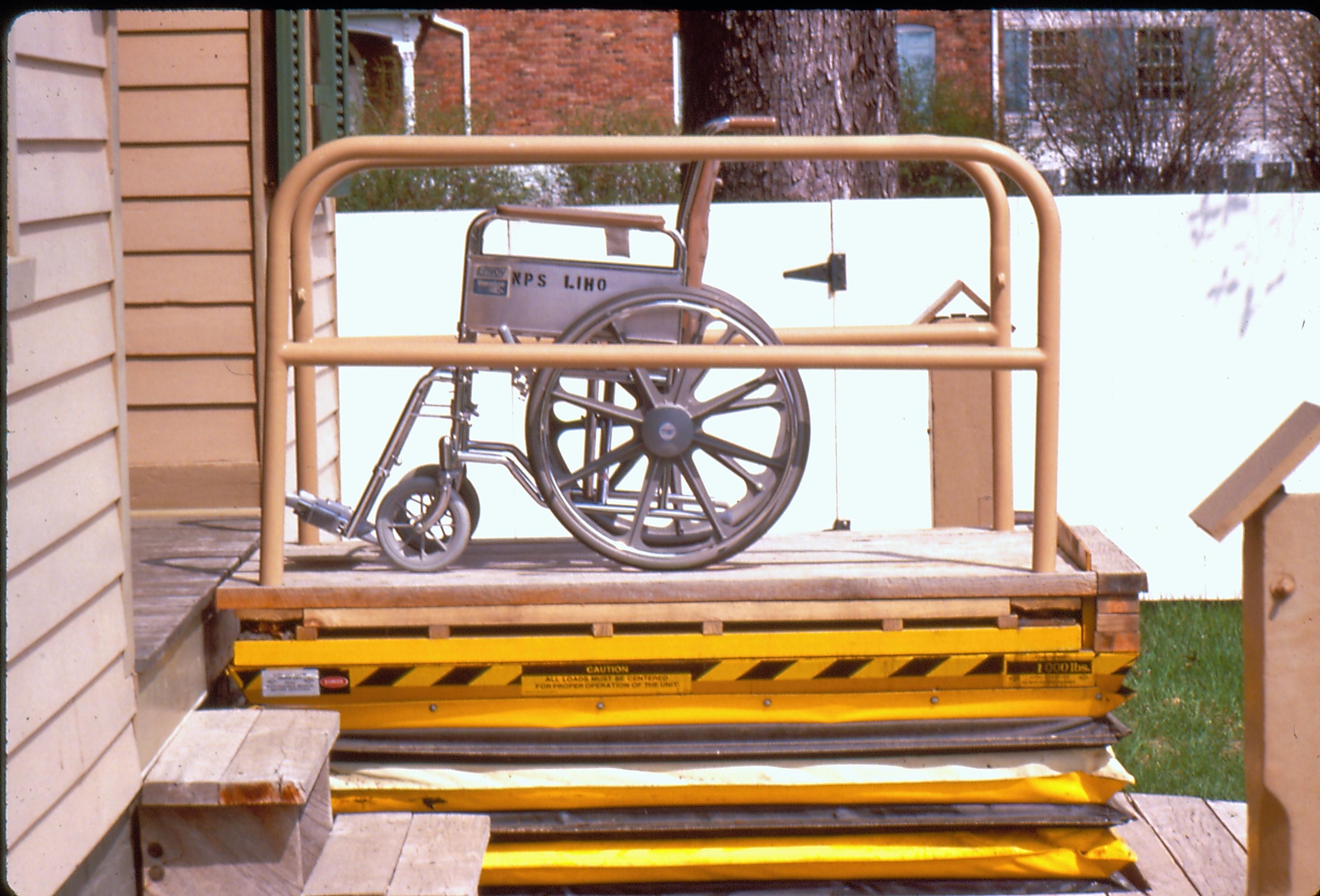 Lincoln Home wheelchair lift at full height, with empty wheelchair. Photographer facing north.