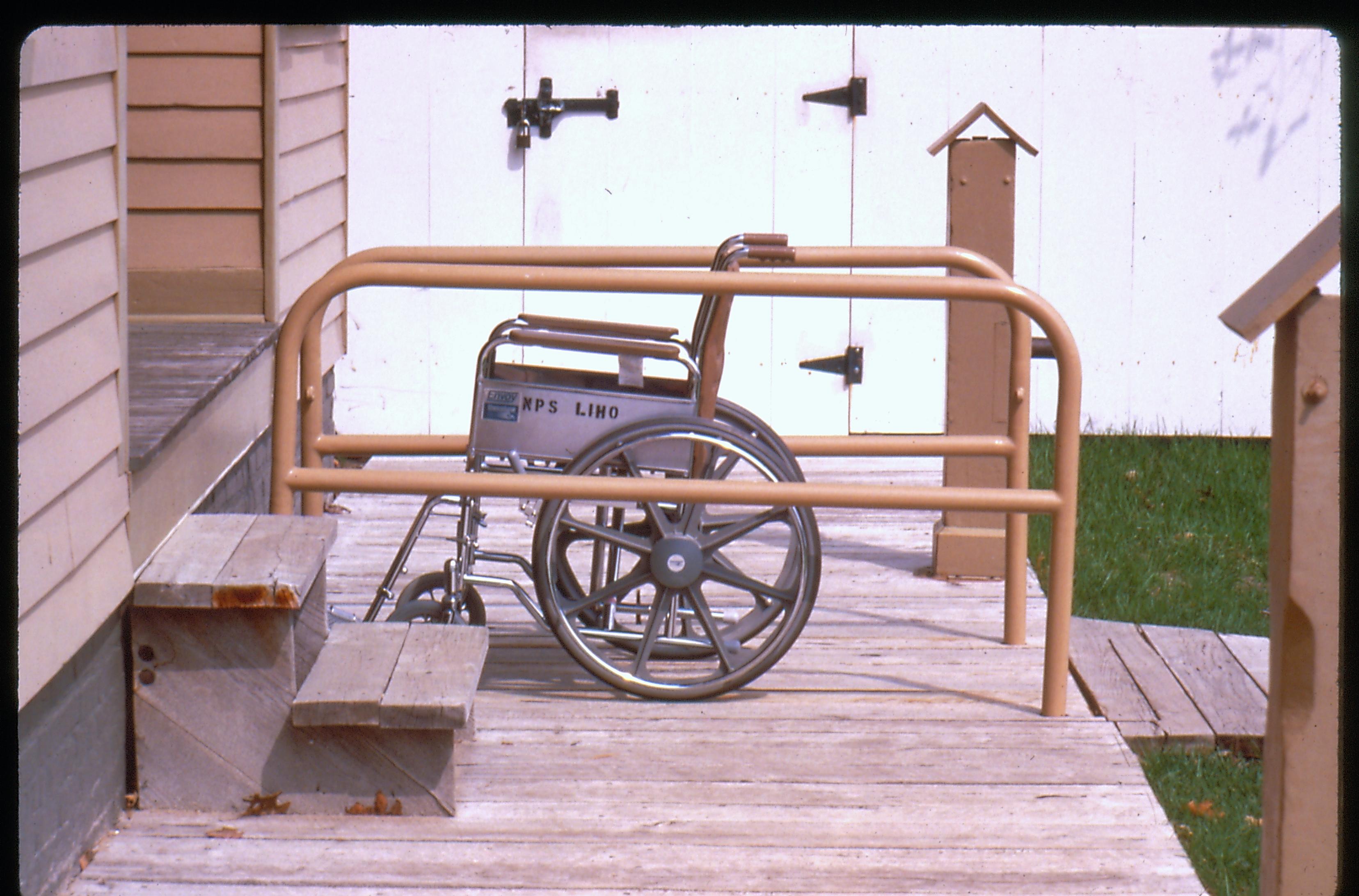 Lincoln Home wheelchair lift while retracted, holding an empty wheelchair. Photographer facing north.