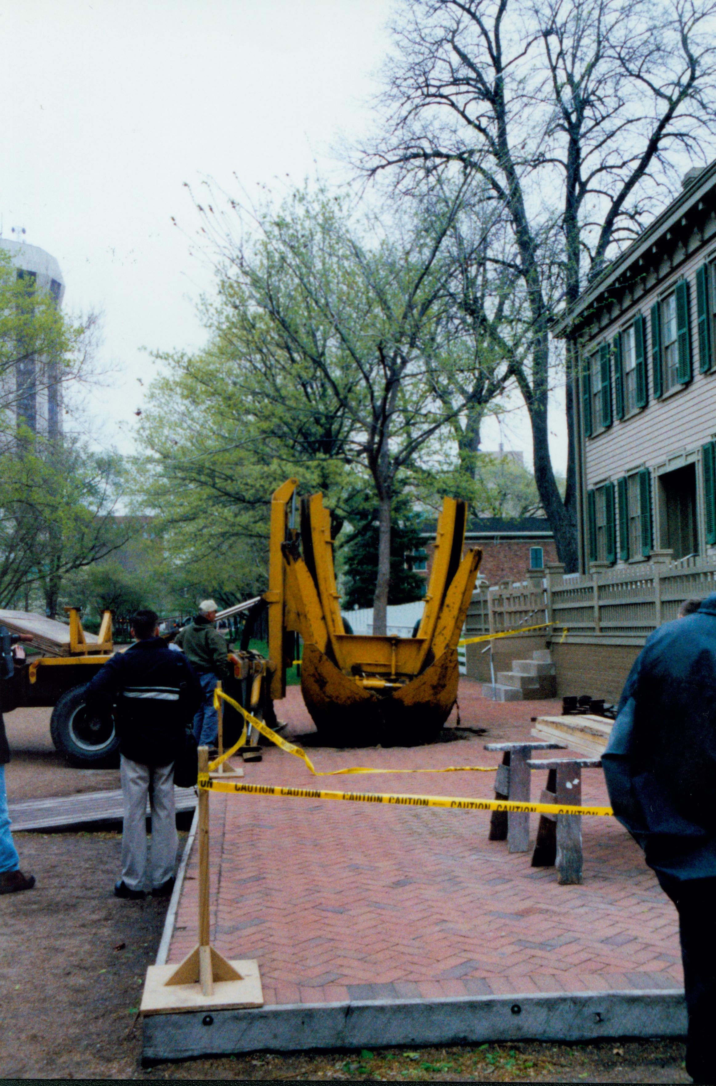 Elm tree replacement - Pleasant Nursery staff removing tree from brick plaza in front of Lincoln Home. Visitors and other nursery staff watch. Conference Center in background center. Hilton Hotel tower in background left. Looking north from 8th and Jackson Street intersection Elm tree, Lincoln Home, brick plaza, Pleasant Nursery, visitors, Conference Center, Hilton Hotel