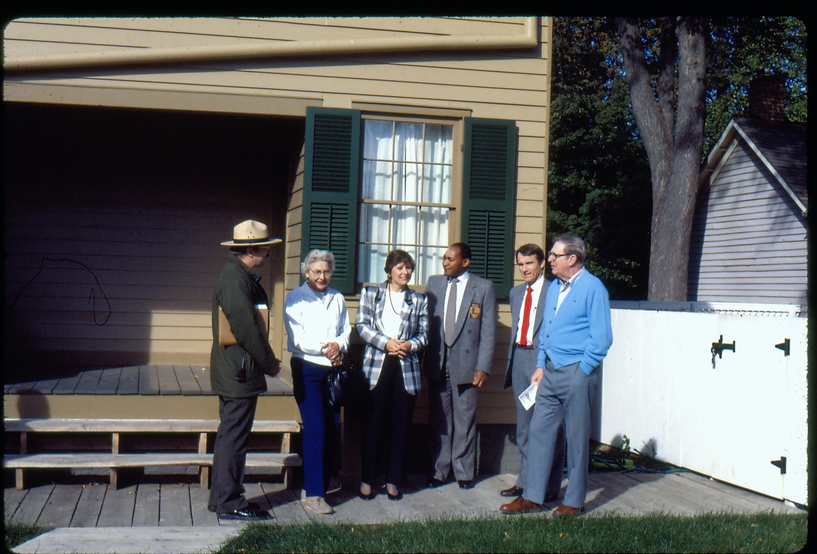 Superintendent Gentry Davis and a second NPS ranger near the Lincoln Home pantry giving a tour to a VIP group after the Restoration of the Lincoln Home. The Corneau House appears in the background. Photographer facing north west.
