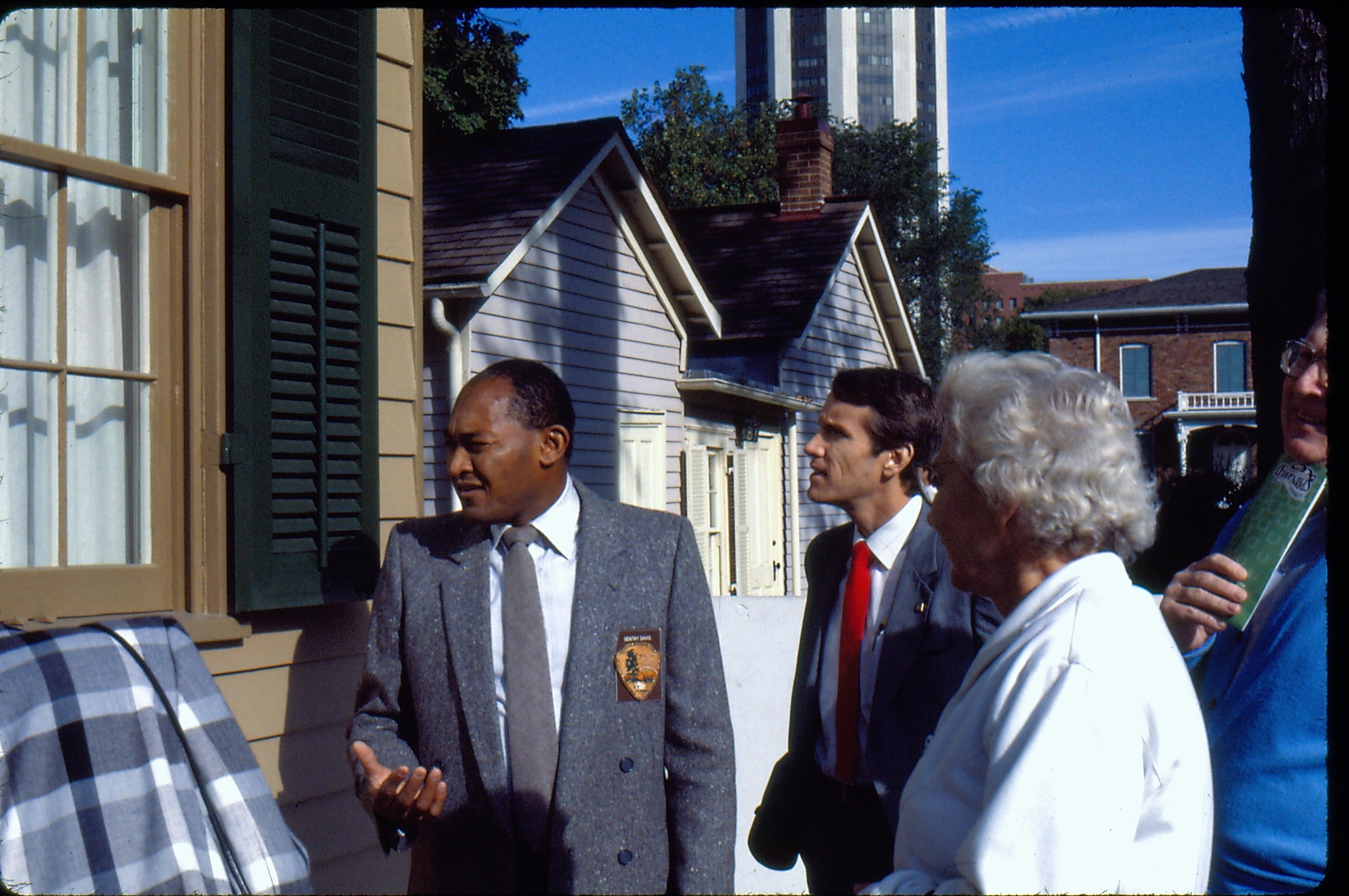 Superintendent Gentry Davis near the Lincoln Home pantry giving a tour to a VIP group after the Restoration of the Lincoln Home. The Corneau House and Conference Center appear in the background. Photographer facing north.