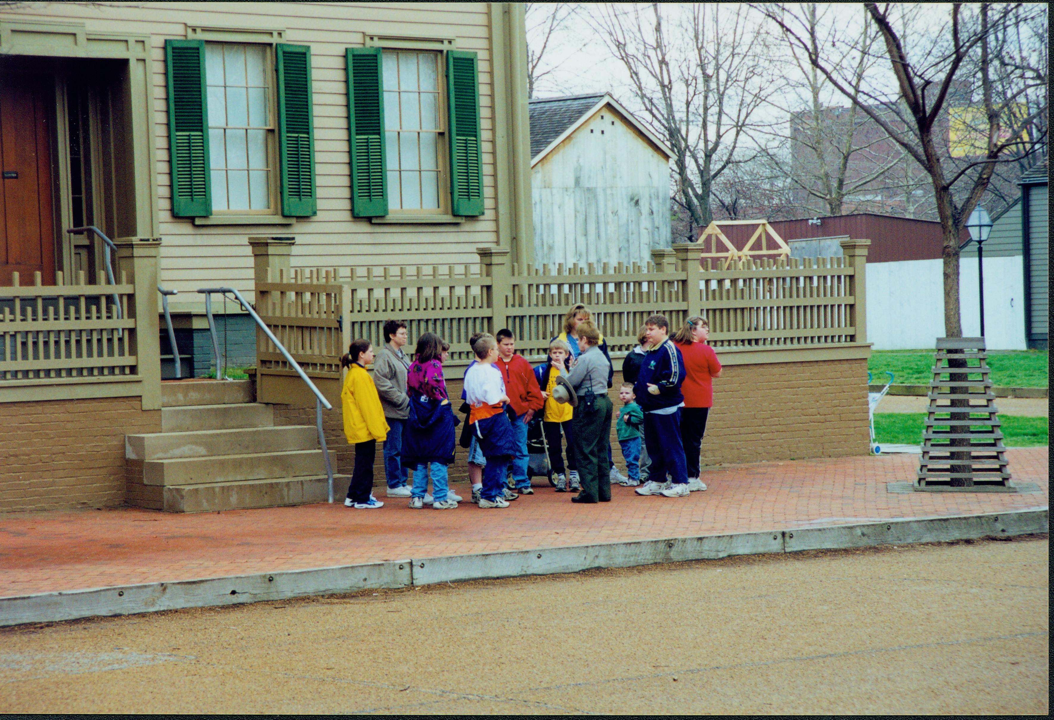 Interpreter Judy Winkelmann speaks with a small group of students in front of the Lincoln Home. Photographer facing south east.