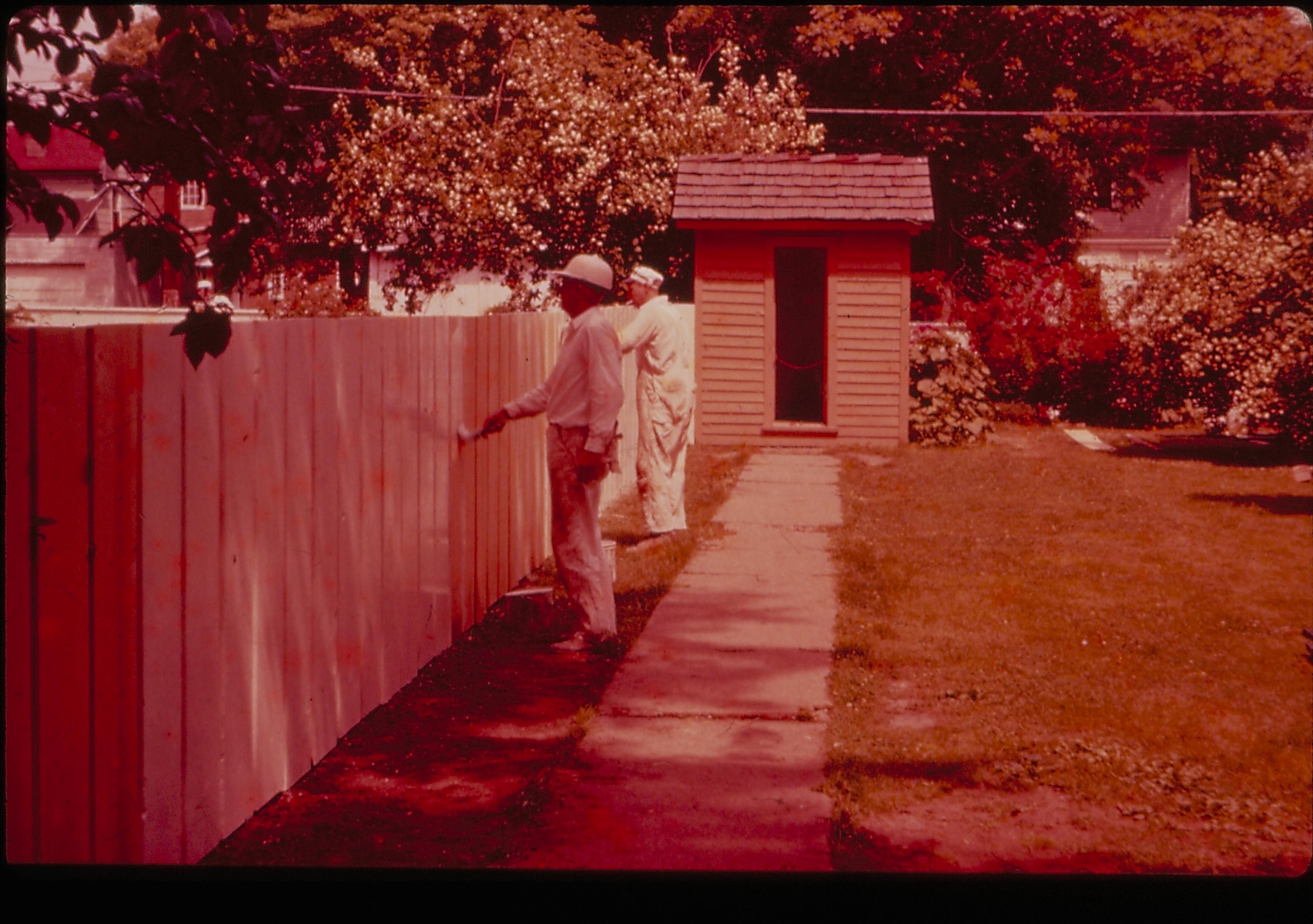Two painters painting the fence on the north side of the Lincoln Home lot. Privy in background. Photographer facing northeast.