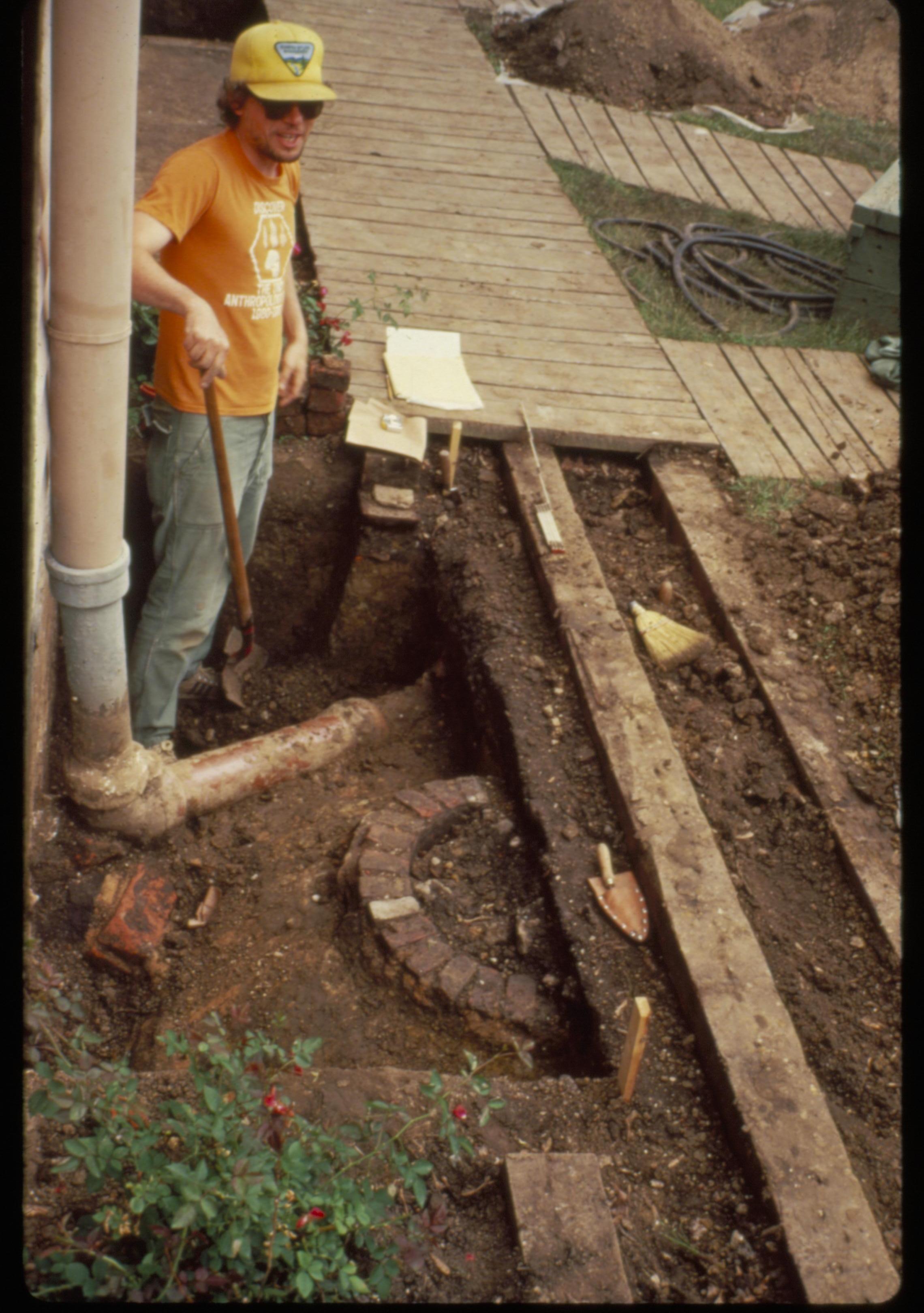 Cistern and water supply/roof drain of the Lincoln Home, in the back yard. Archeologist stands while digging. Photographer facing north.
