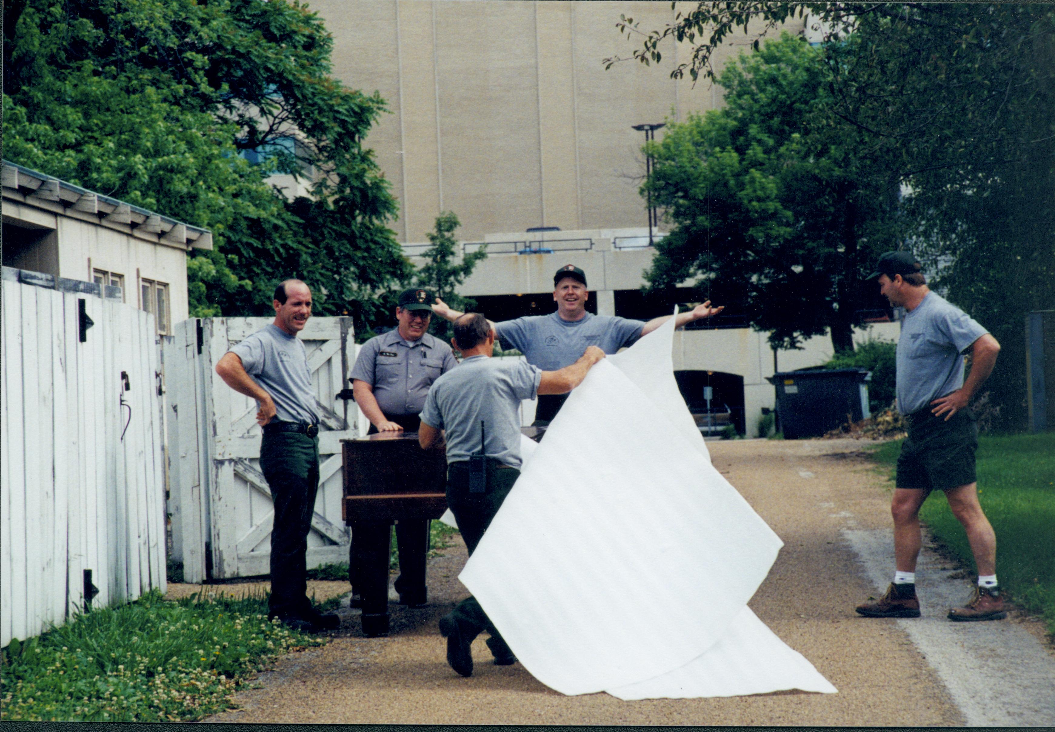 Members of Maintenance moving piano from Carriage House storage area to new location in Arnold Barn Lincoln Home NHS, 1998 CRS Collection Move, East alley, Roll N7, exp 6 sheet 2 of 9 Carriage House, storage room