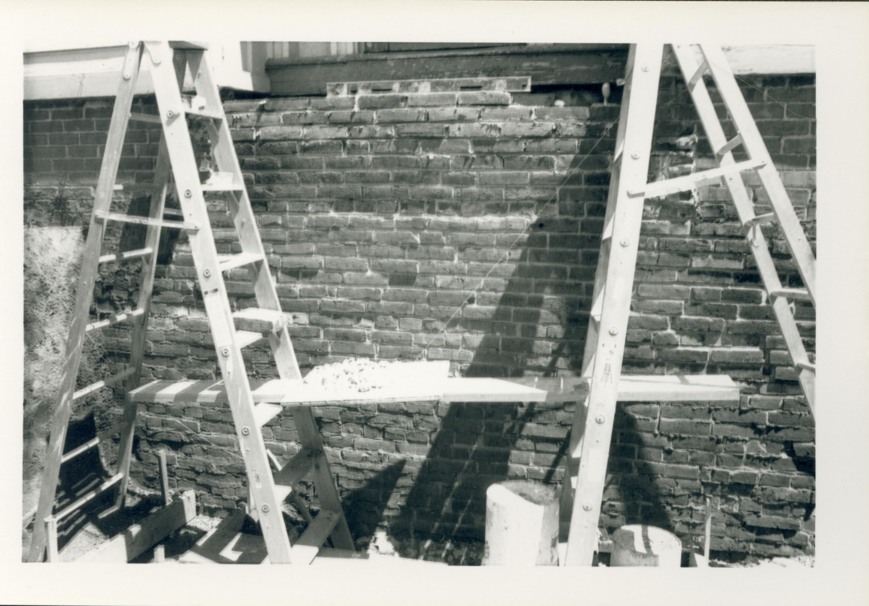 Two ladders in a trench alongside an exposed section of the Lincoln Home foundation during the 1987-1988 restoration. The west entrance to the Lincoln Home can be seen at top.