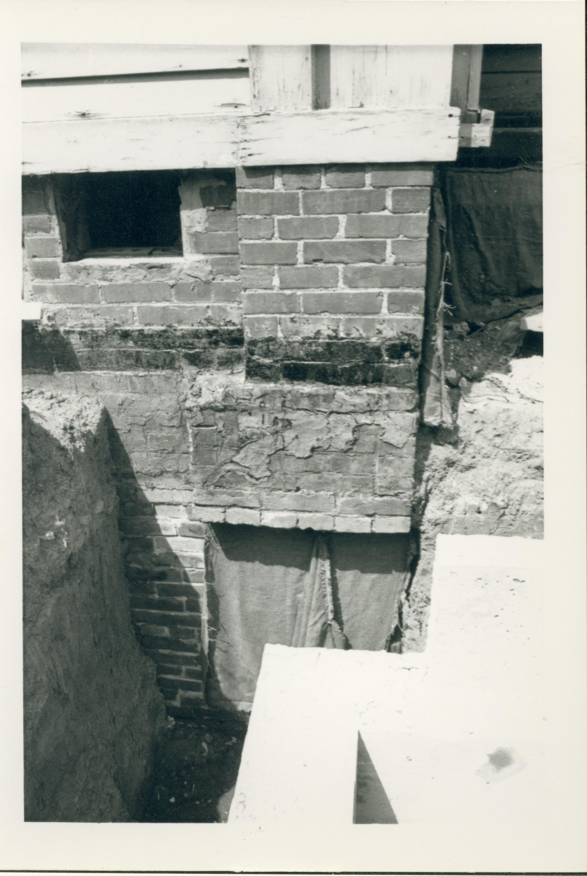 An exposed section of the south face of the Lincoln Home foundation uncovered during the 1987-1988 Restoration. The south porch and a basement window can be seen. Photographer facing north.