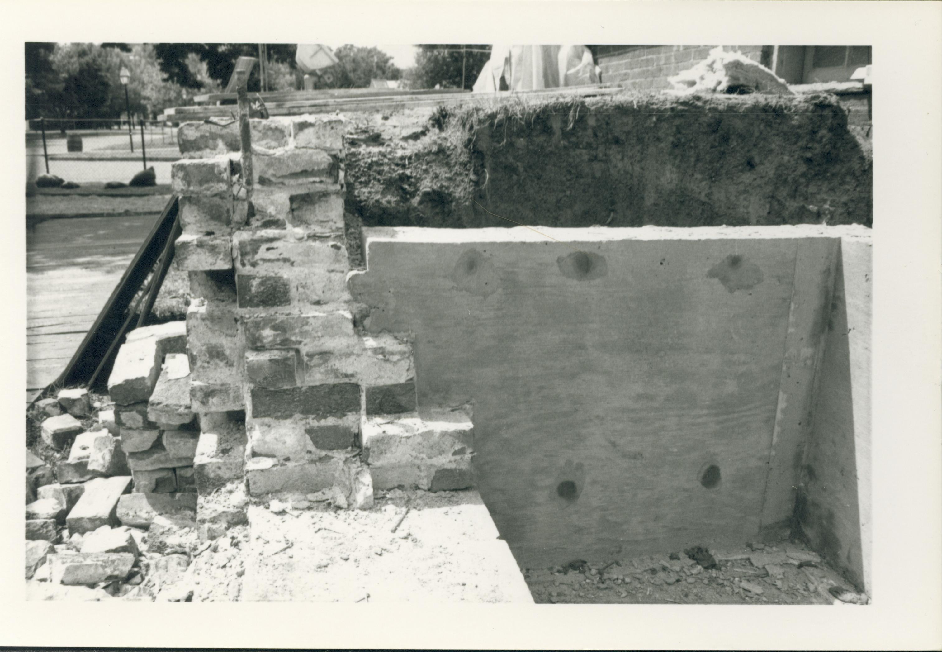South face of Lincoln Home retaining wall and section of south yard during the 1987-1988 Restoration. A section of the foundation, boardwalk, and Eighth Street can be seen. Photographer facing west.