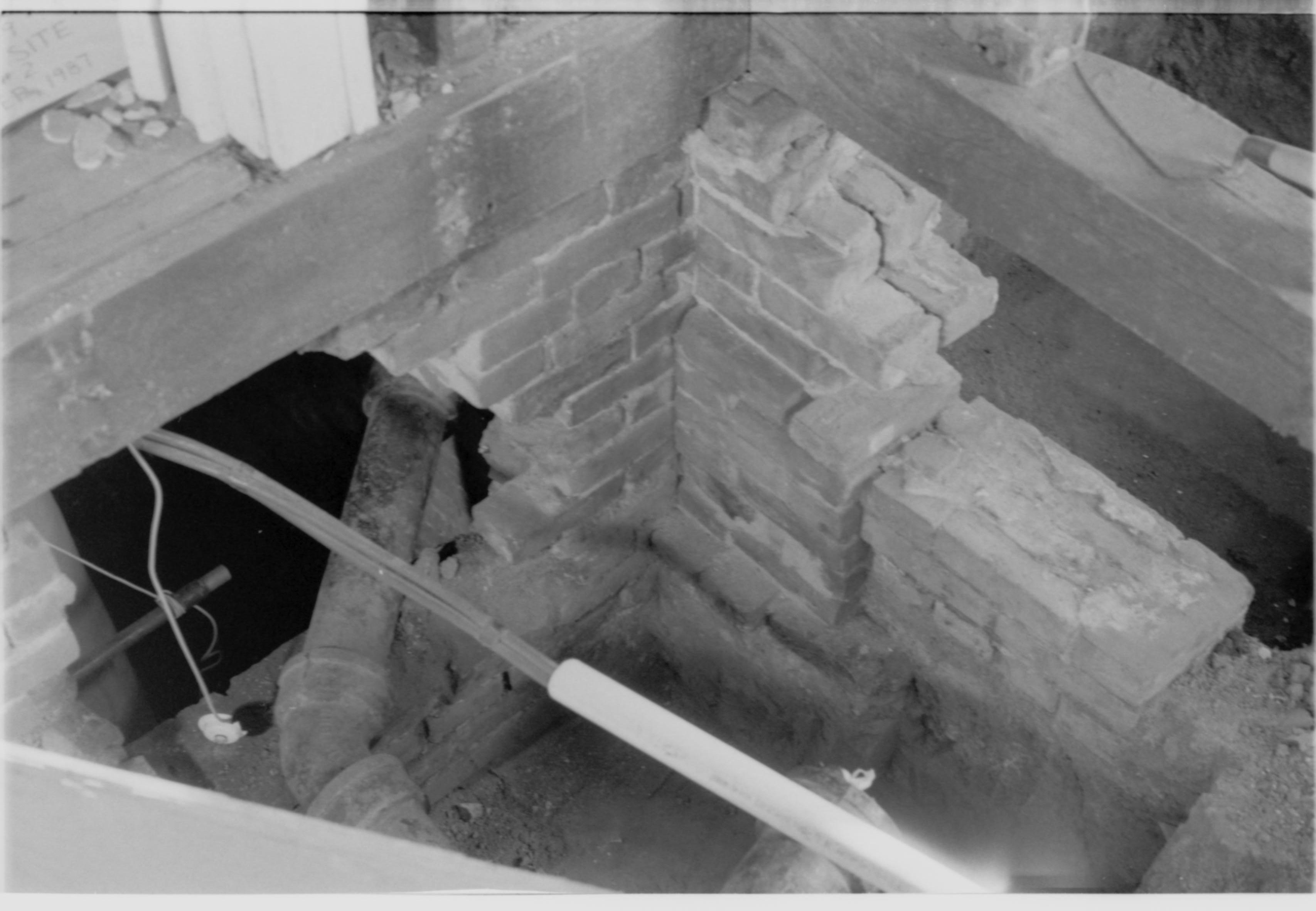Morse House HS-9 Test Site #3. Brick stair leading into house. Porch sill with void to right of picture. Door frame, with foundation header, in left and middle of picture. Hole in foundation, with conduit, in foreground.