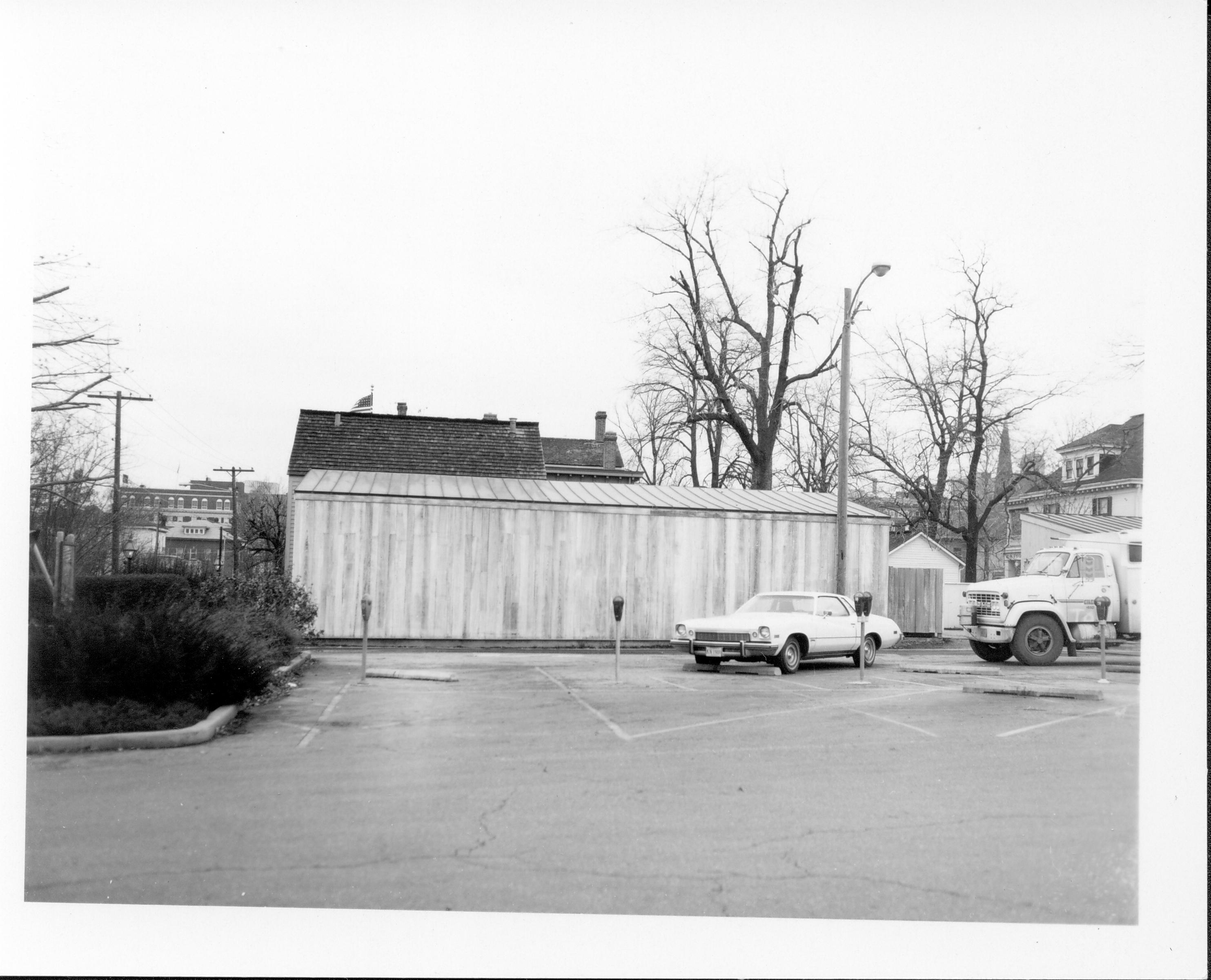 Lincoln Home woodshed. Roof of Lincoln Home in background, with visitor parking lot in foreground. Photographer facing west.