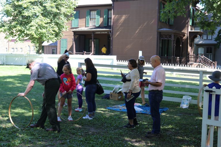 Park Guide, Max Farley, demonstrates the toy of Hoop and Stick for some young visitors.