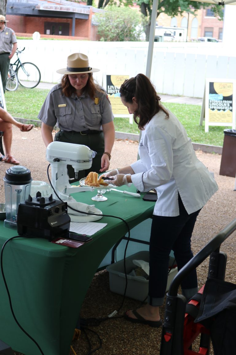 Park Ranger, Linsey Hughes prepares to hand out samples of Mrs. Lincoln's White Almond cake. As part of History Cooks for History Comes Alive, Chef Jolene Lamb, demonstrates how to make Mrs. Lincoln's famous White Almond cake. History Cooks is a partnership between Lincoln Home, Lincoln Land Community College/Jay Kitterman and Springfield Convention and Visitor's Bureau.